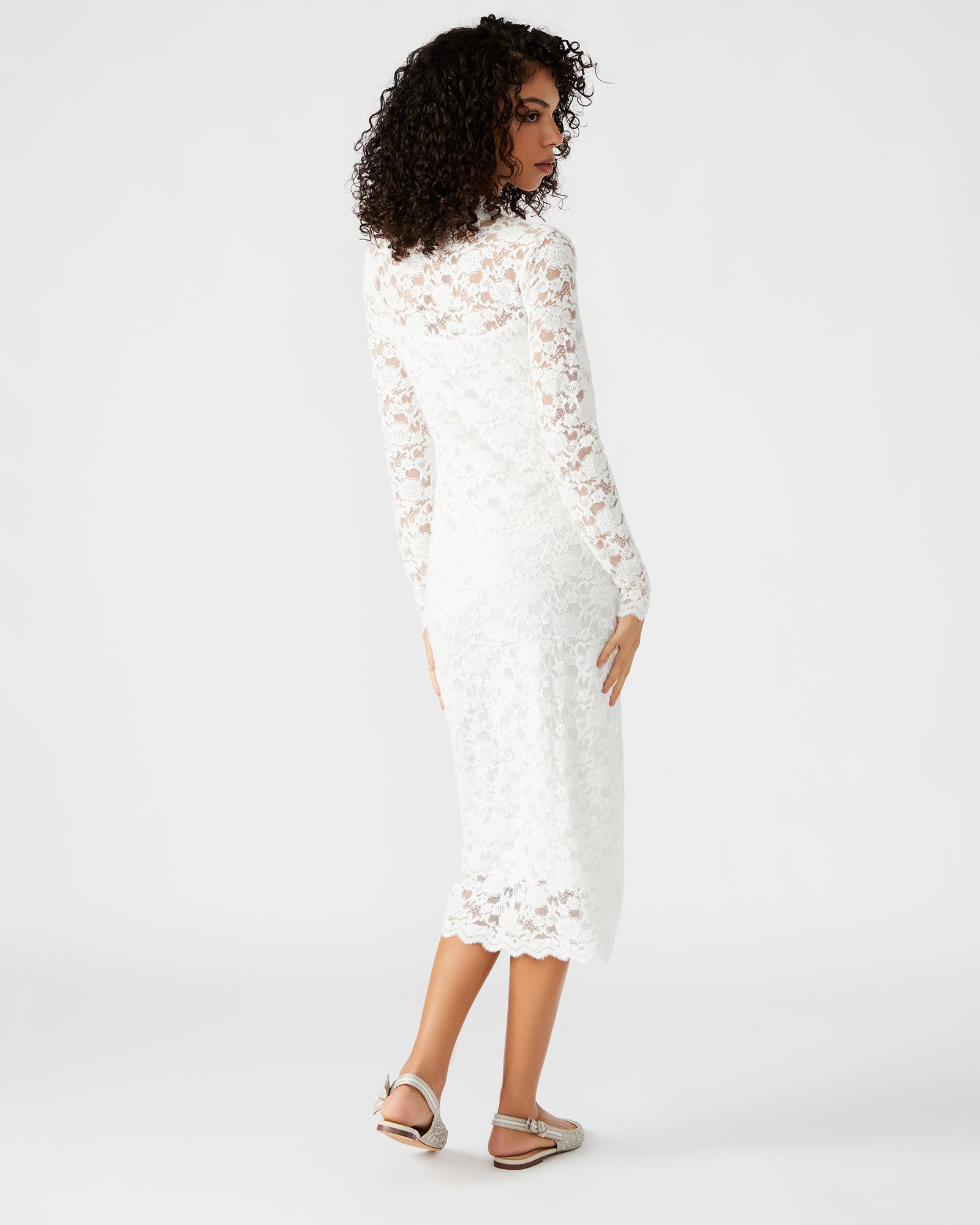 Side angle of the white lace dress worn with heels in a New York rooftop setting.