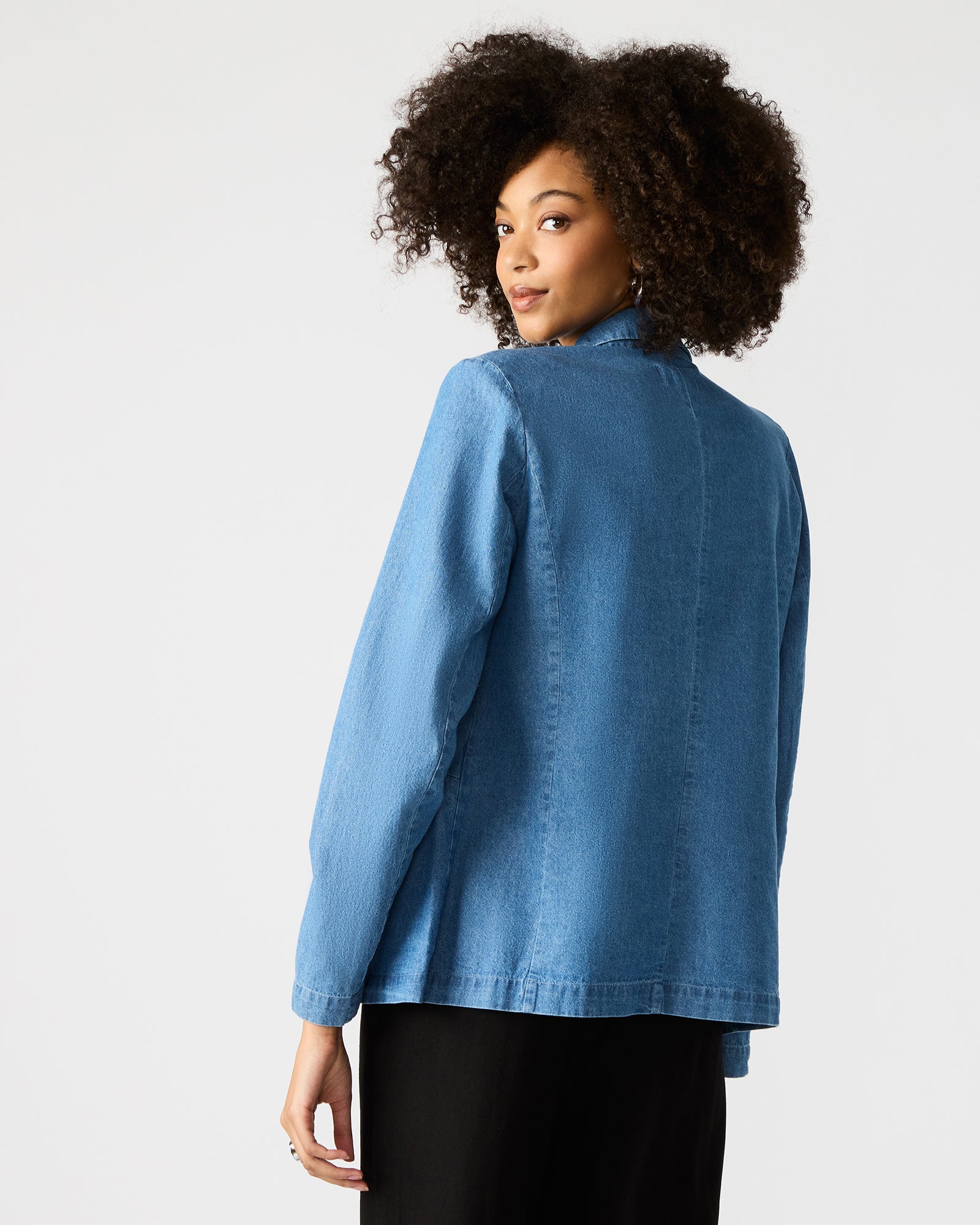 Front view of denim blazer women styled over white tee and trousers