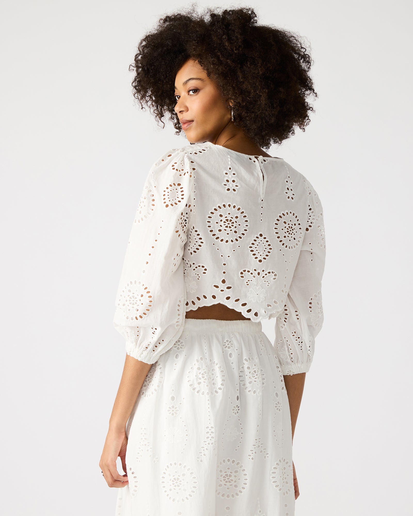 Front view of white crop top with eyelet details and long sleeves, styled casually