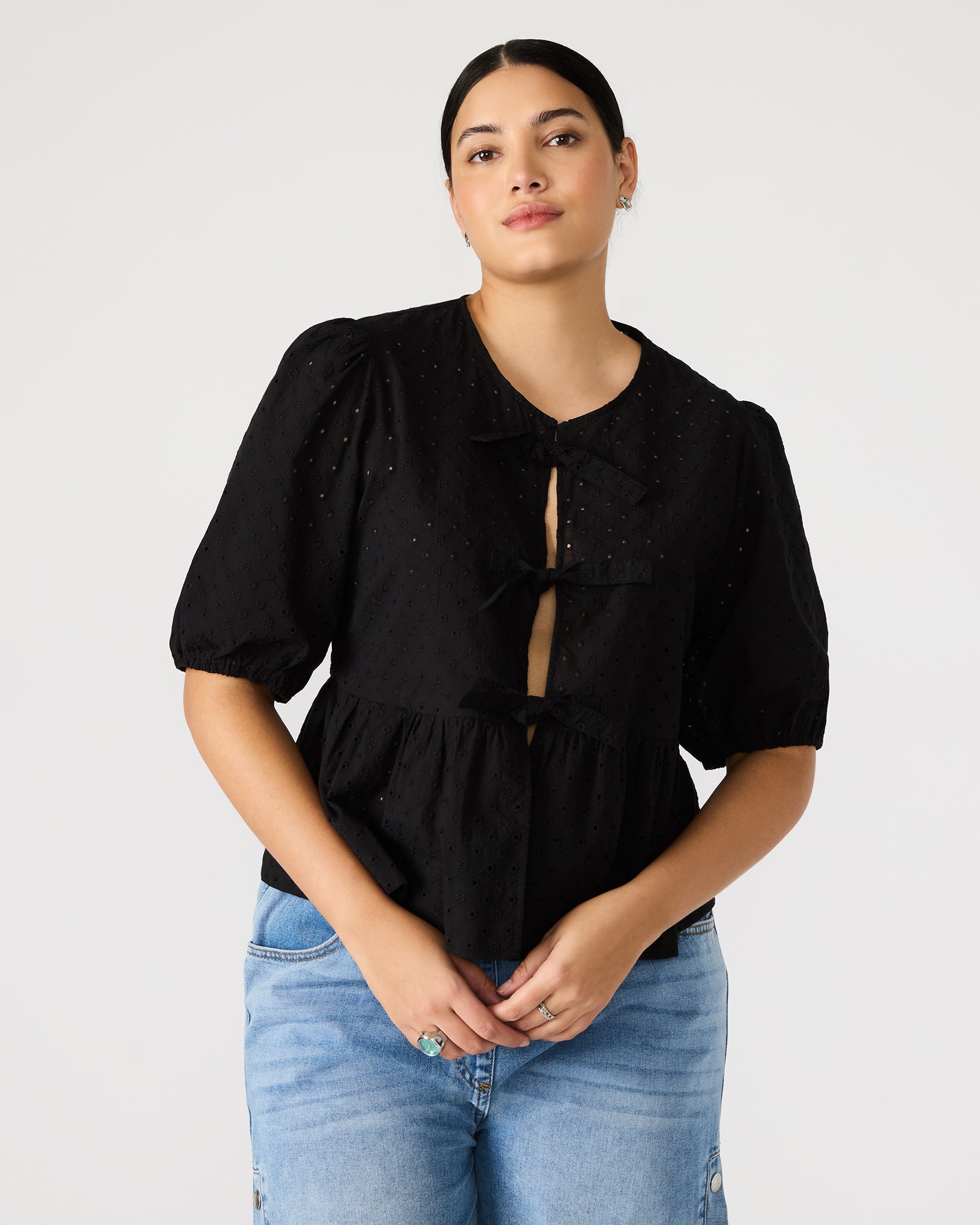 Front view of the black puff sleeve tie-front top on a model.