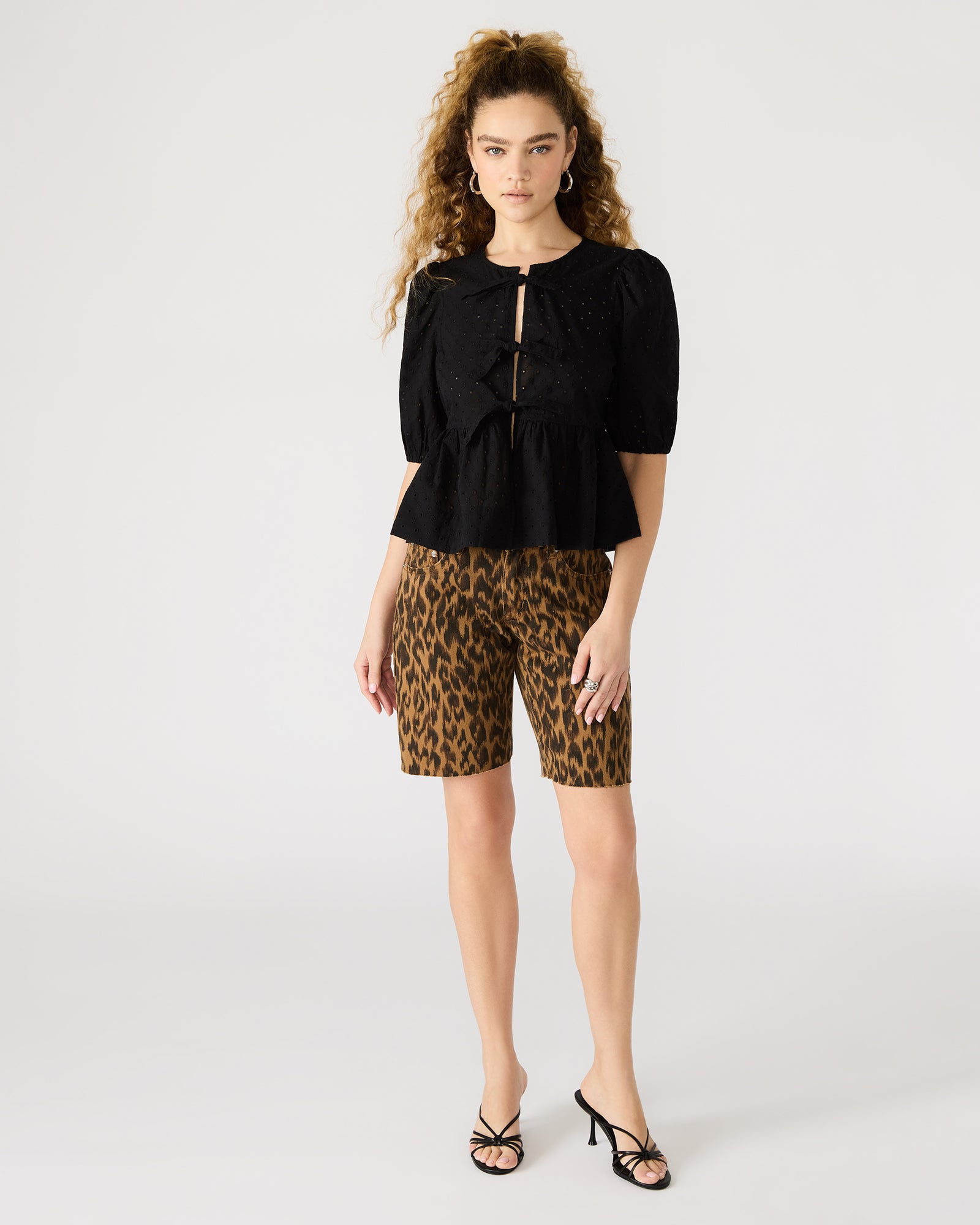 Front view of the black puff sleeve tie-front top on a model.