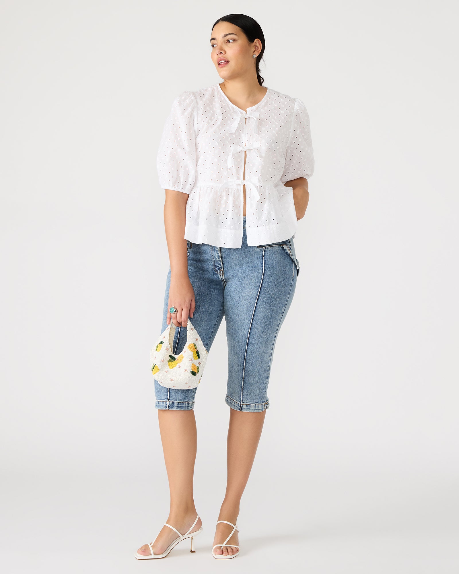 Close-up of the puff sleeves and eyelet detailing on the chic white top.