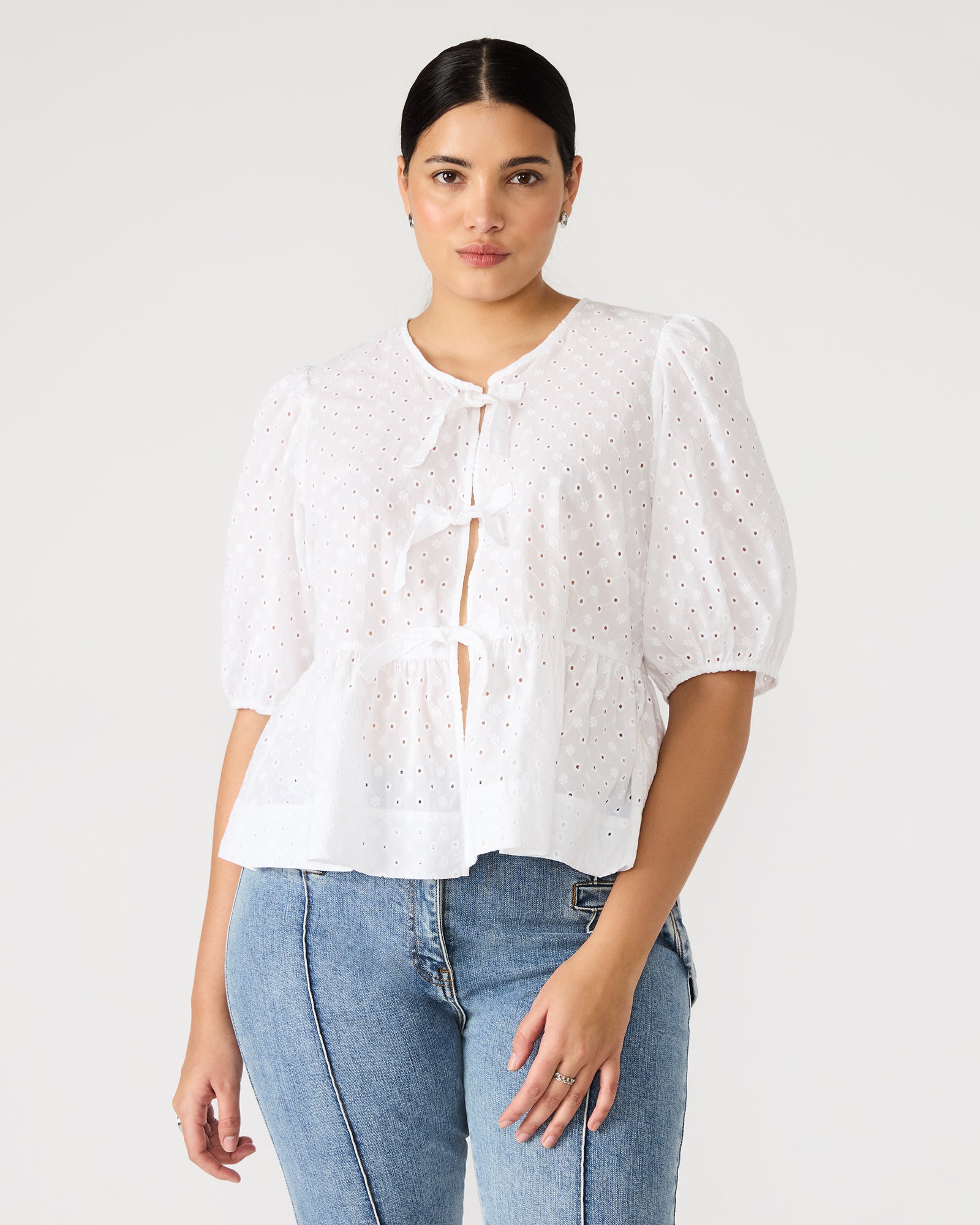 Front view of the chic white puff sleeve crop top showcasing its tie-front design and eyelet detailing.