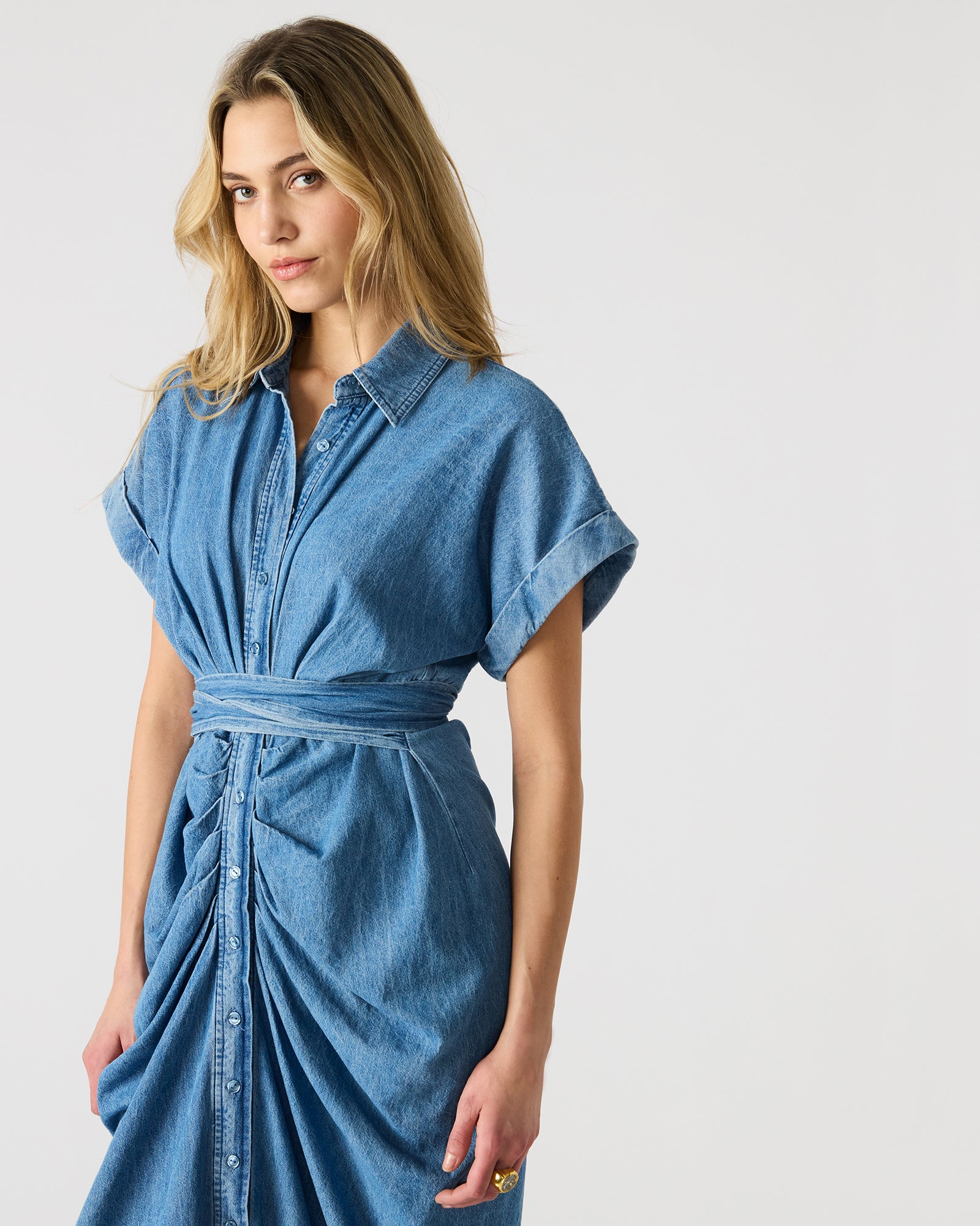 Close-up detail of cuffed sleeve and button-up design on denim fabric