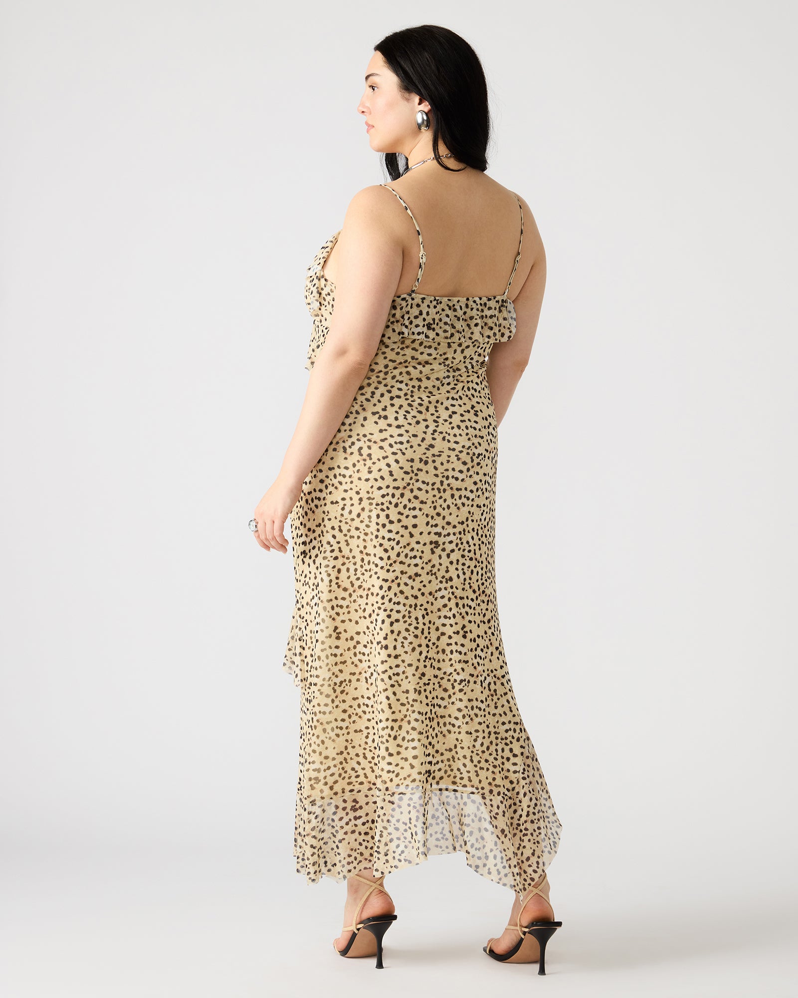 AIDA dress showing flowy ruffle design in a sunny garden setting.