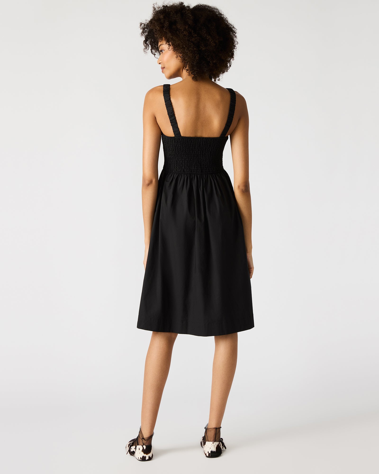 Black cotton midi dress draped elegantly on a model, showcasing smocked detail