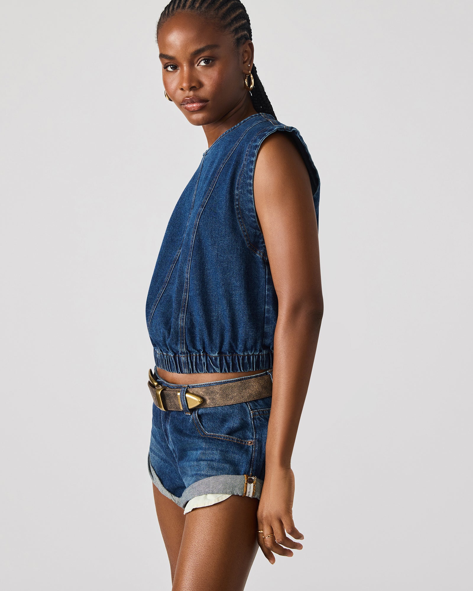 Back angle showing zipper detailing on sleeveless top styled with hoop earrings.