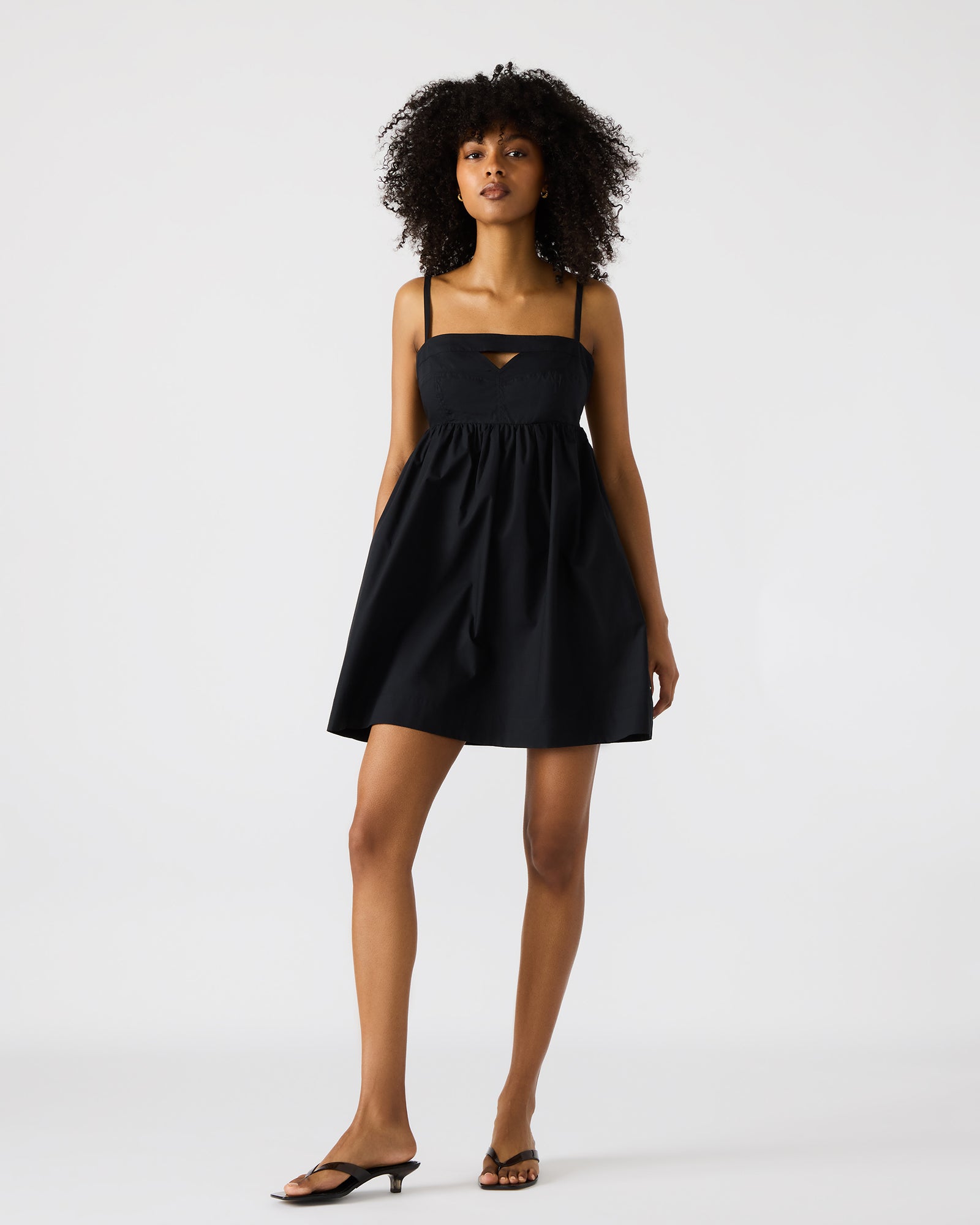 Front view of black mini dress with cutout detail, worn in an urban setting