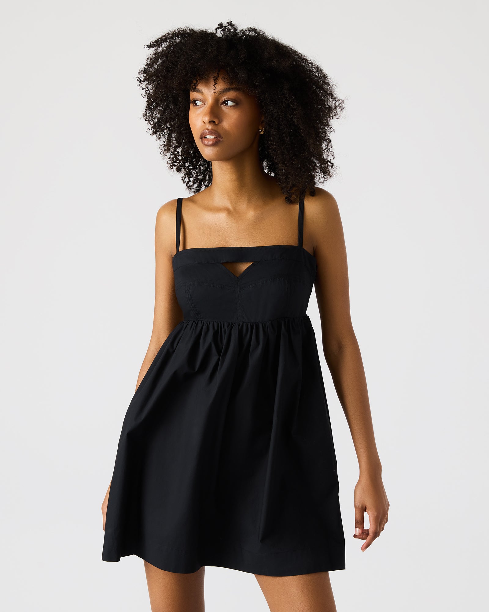 Front view of black mini dress with cutout detail, worn in an urban setting