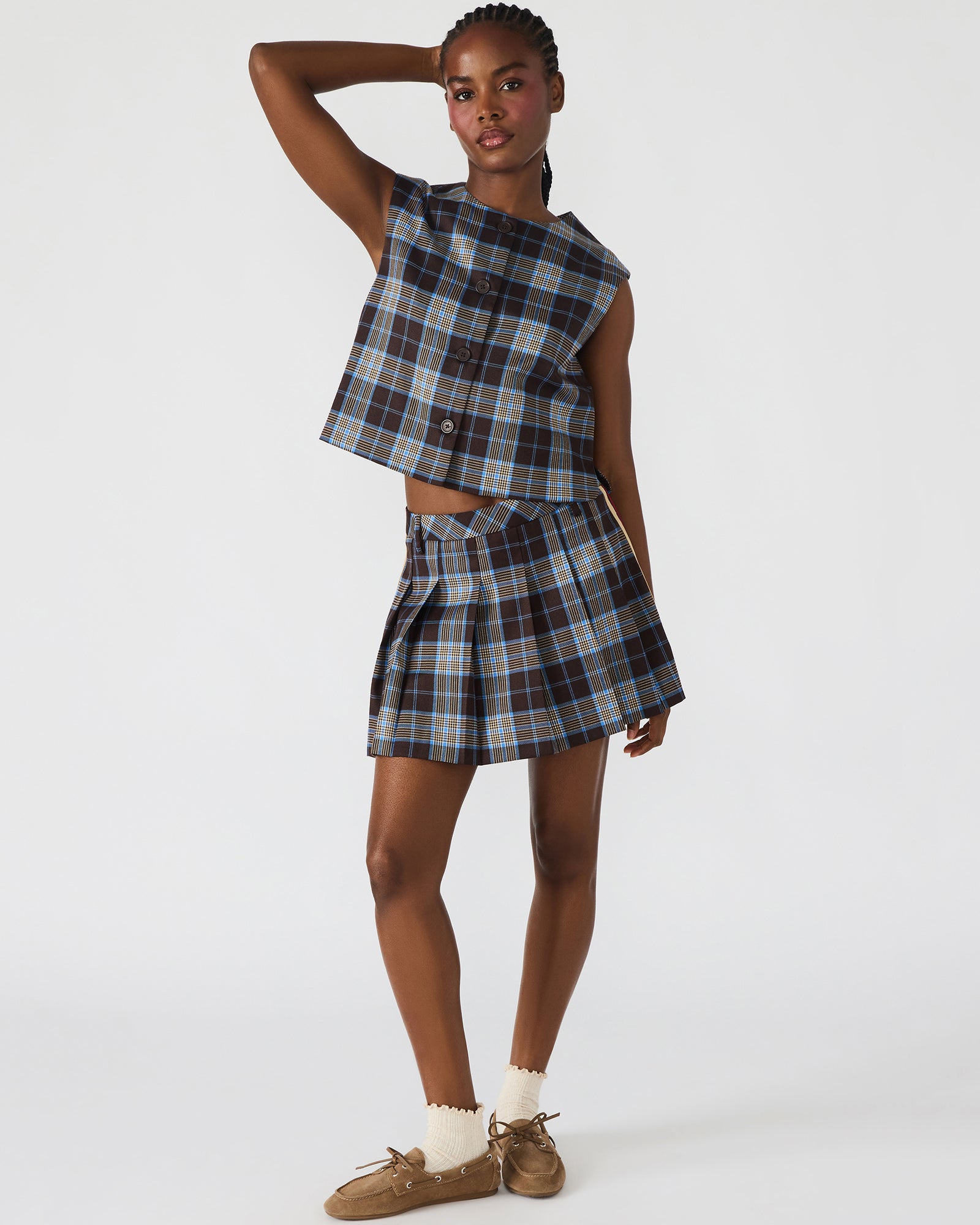 Model wearing the brown plaid pleated mini skirt paired with a simple top for a daytime look