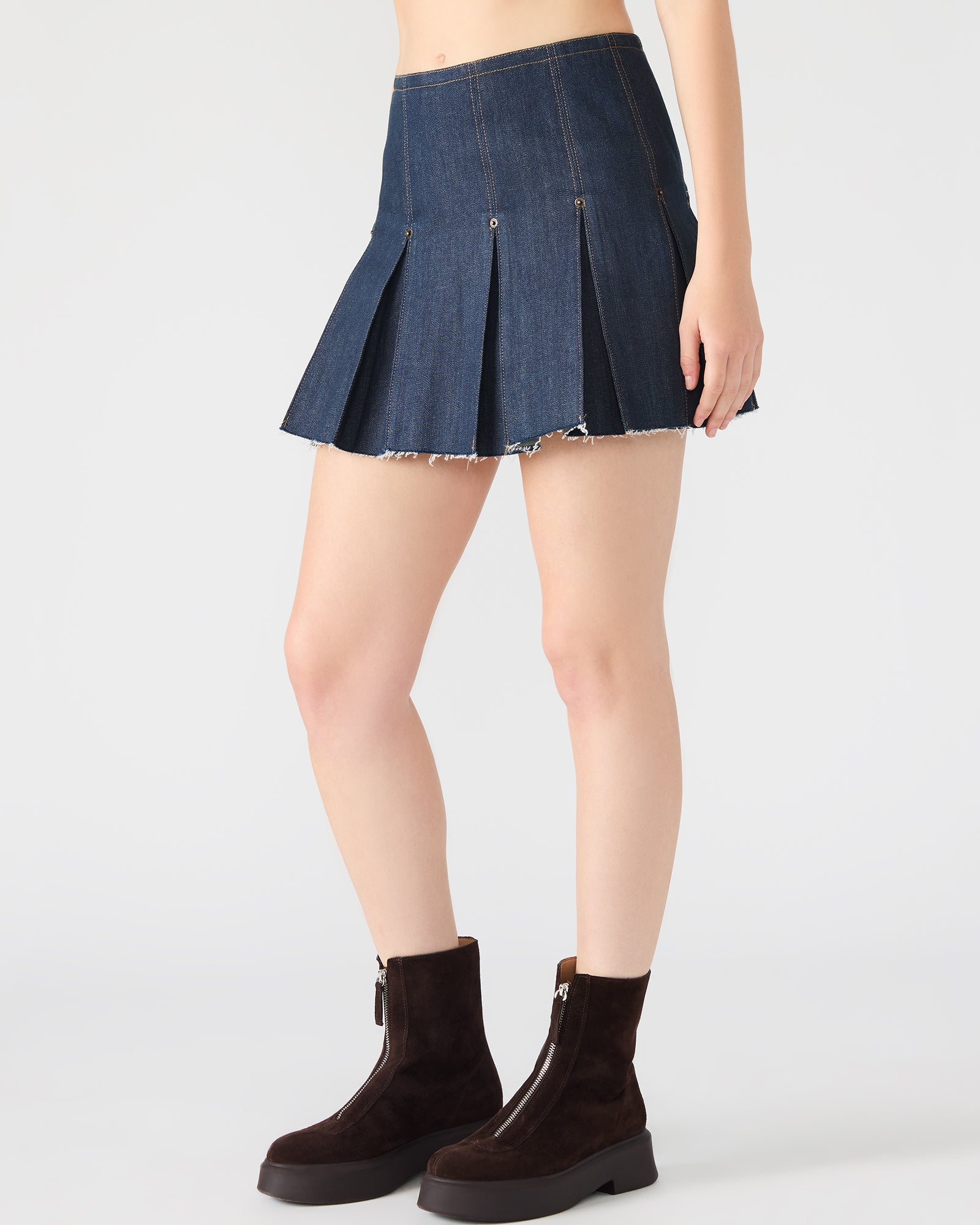Close-up of the Joan pleated denim mini skirt in deep indigo showing the pleats and texture