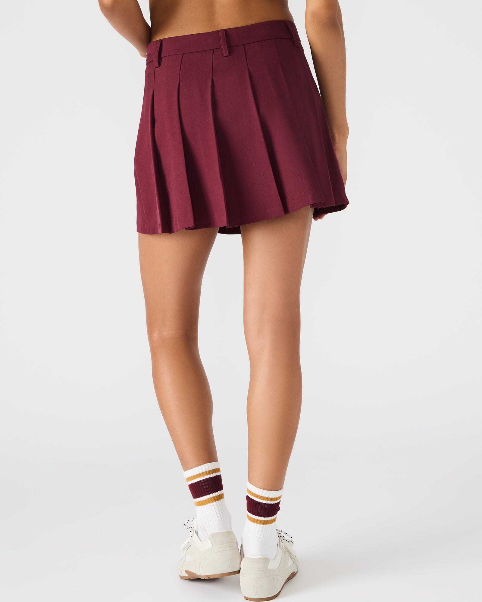 Back angle showcasing belt loops and movement of pleated skirt in motion