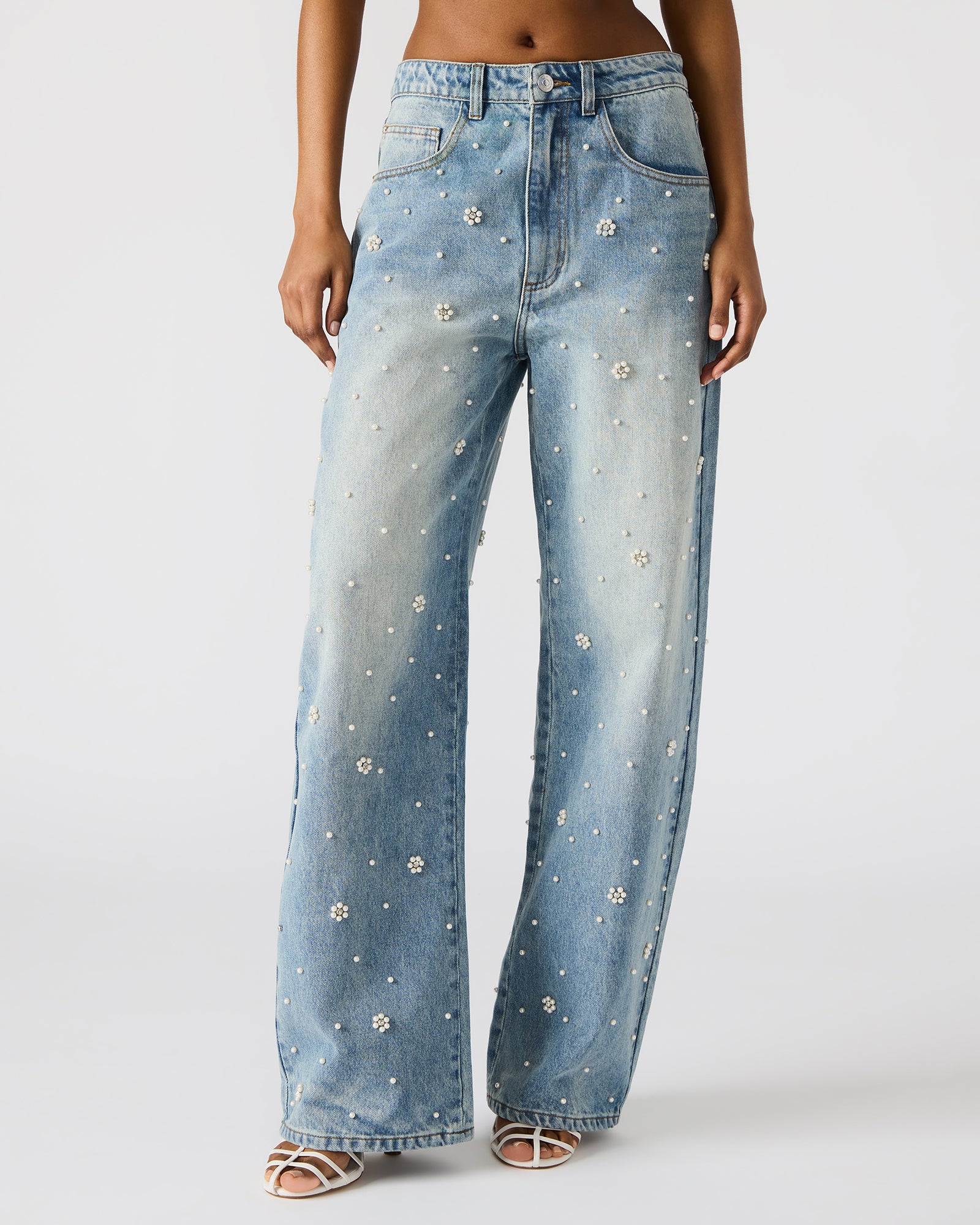 Close-up of pearl flower accents on black wide leg jeans