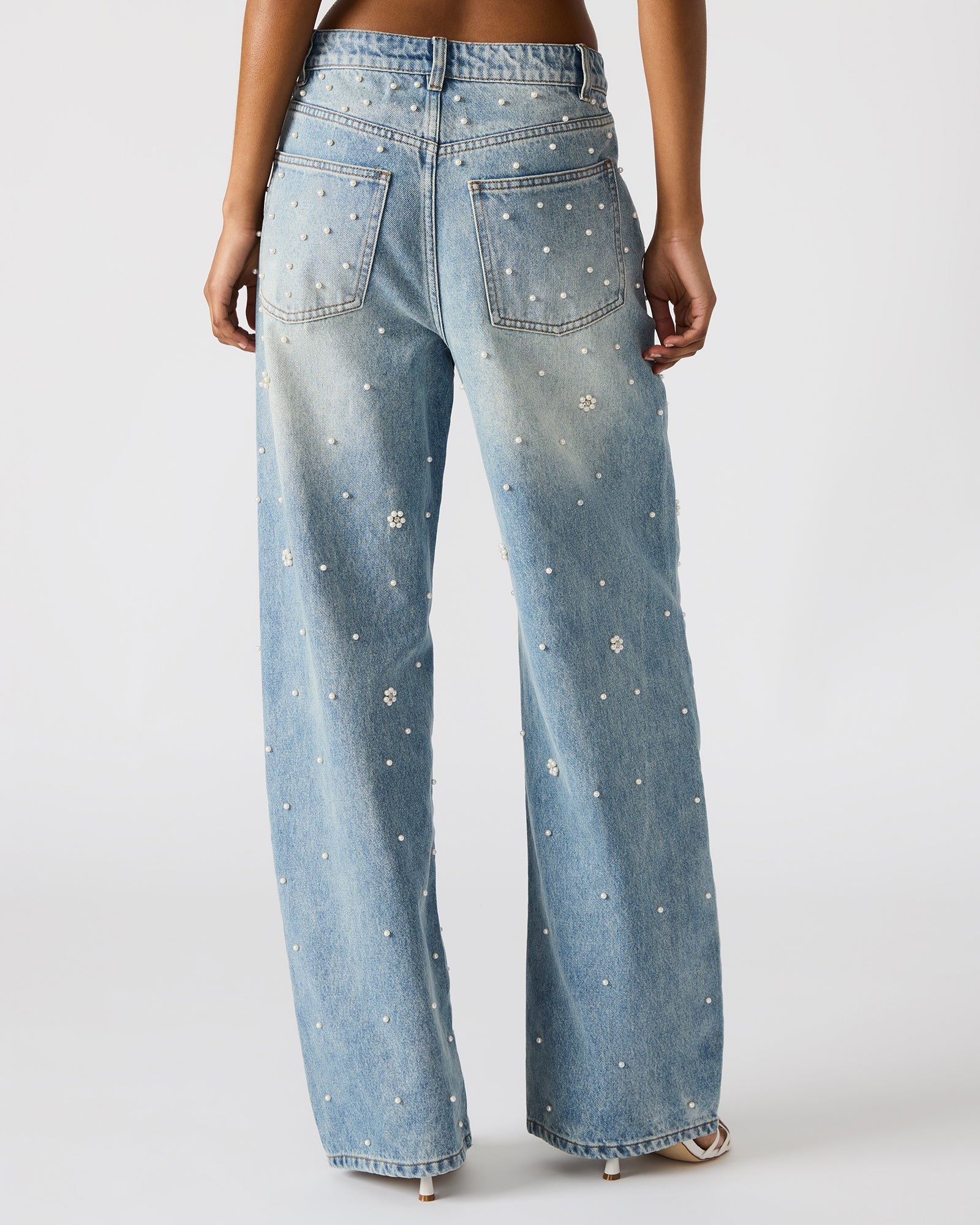 Front view of womens wide leg jeans with pearl embellishments, styled with heels