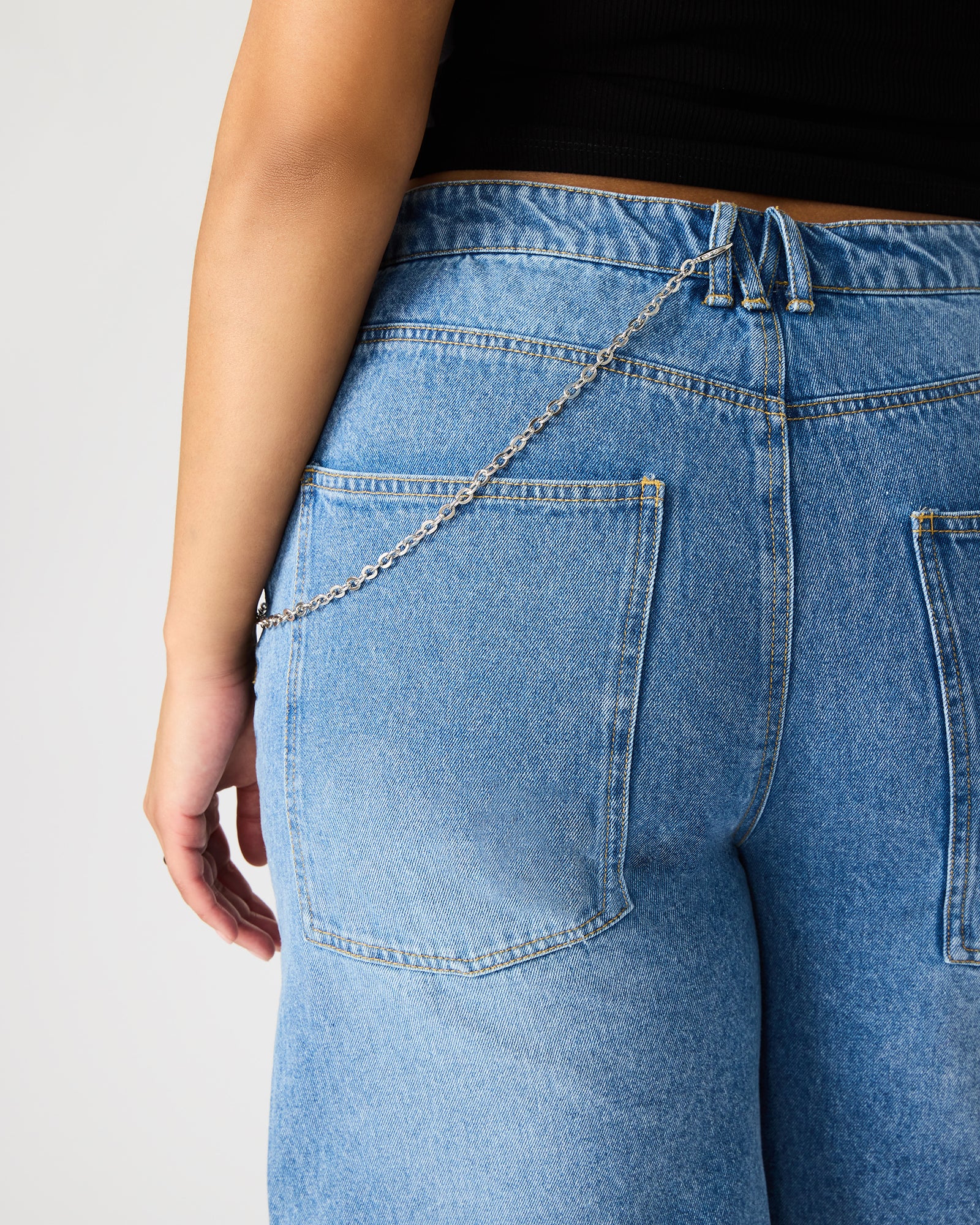 Close-up of the zipper and button closure on women’s denim shorts