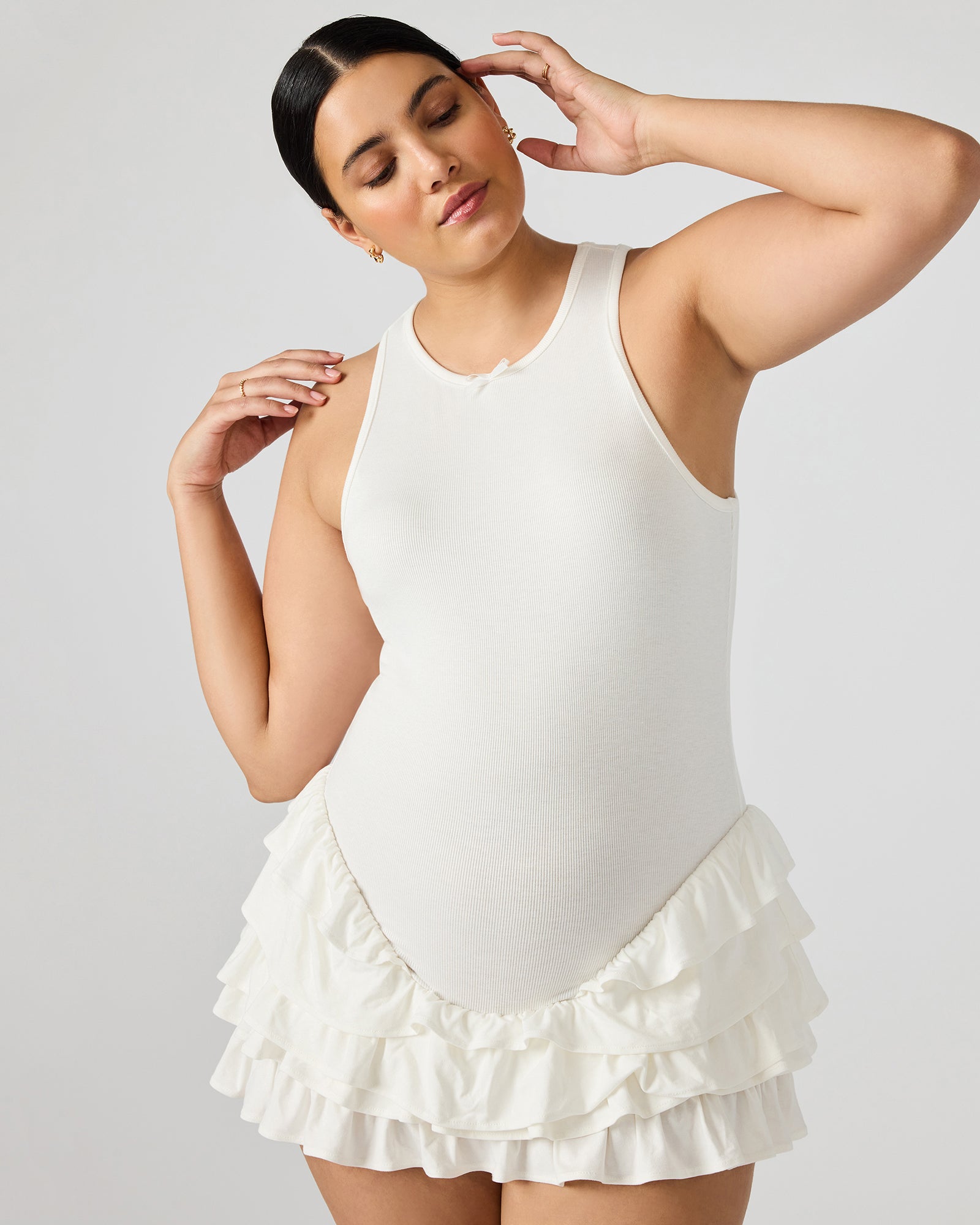 Close-up of the ruffled hem detail on the white mini dress