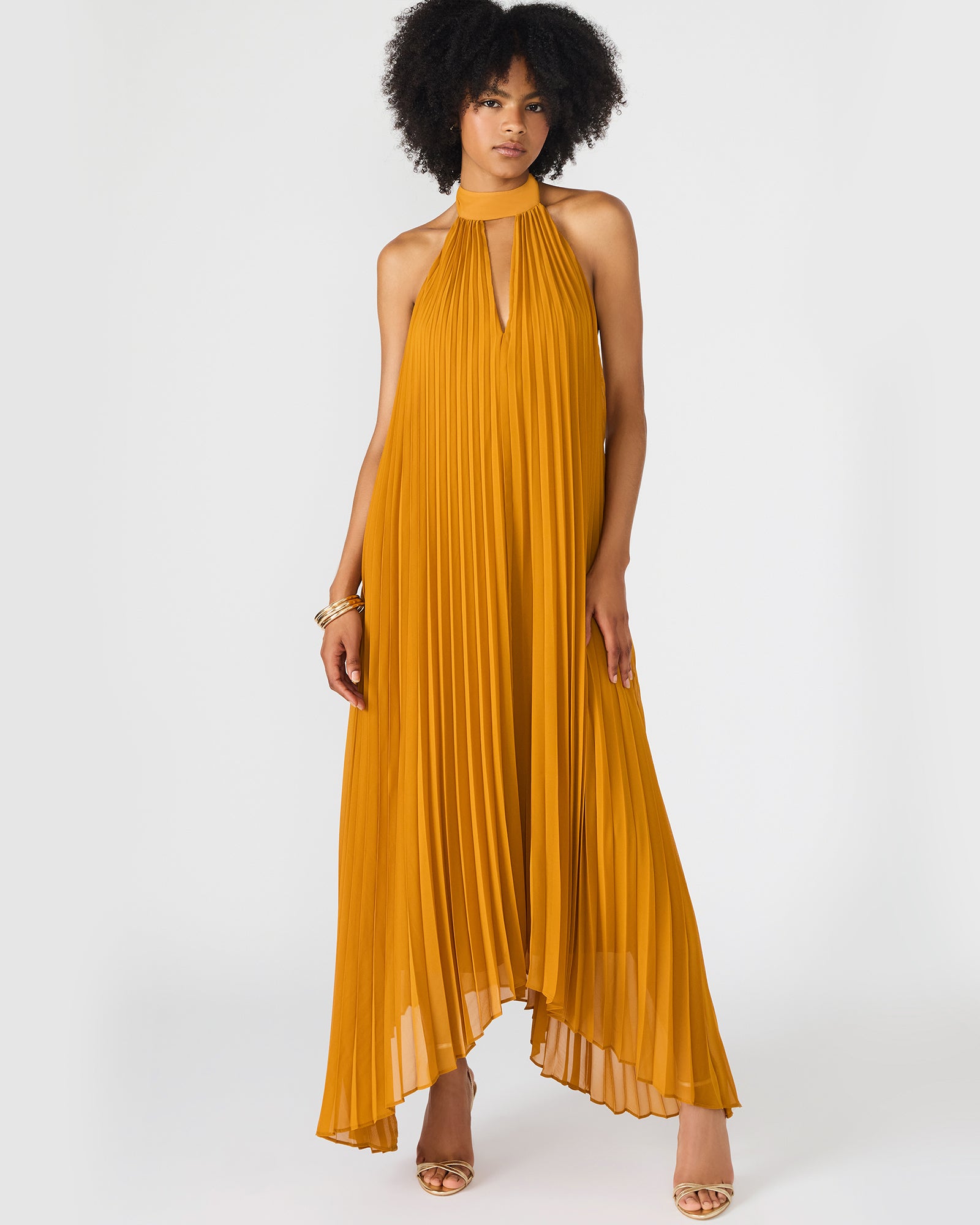 Model wearing halter neck dress walking through city streets at sunset