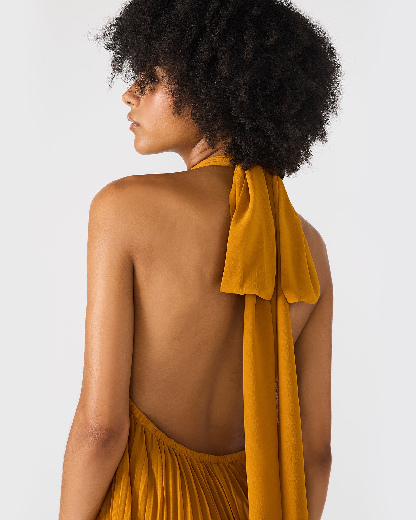 Model wearing halter neck dress walking through city streets at sunset