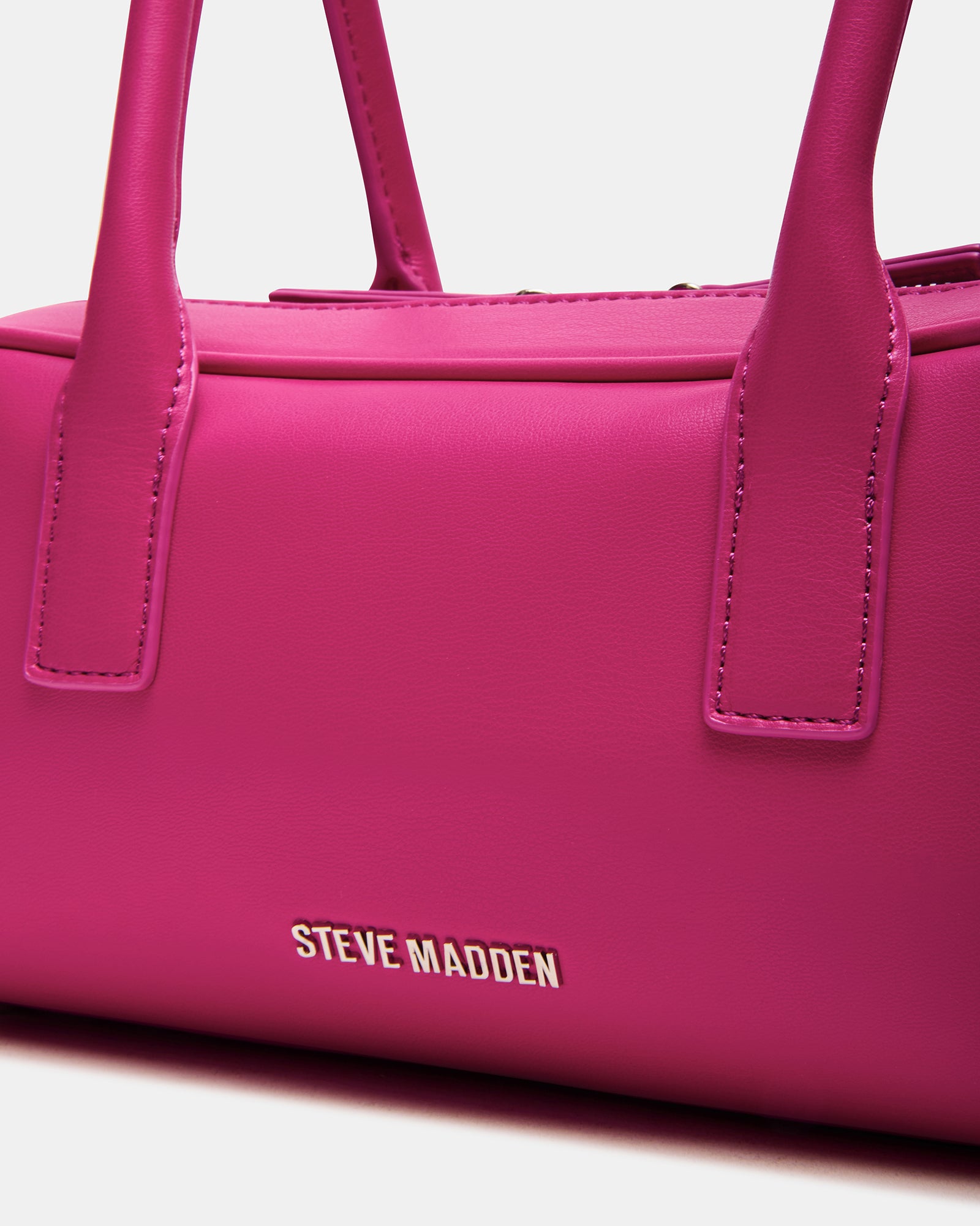 Model showcasing the fuchsia coach shoulder bag in an urban setting