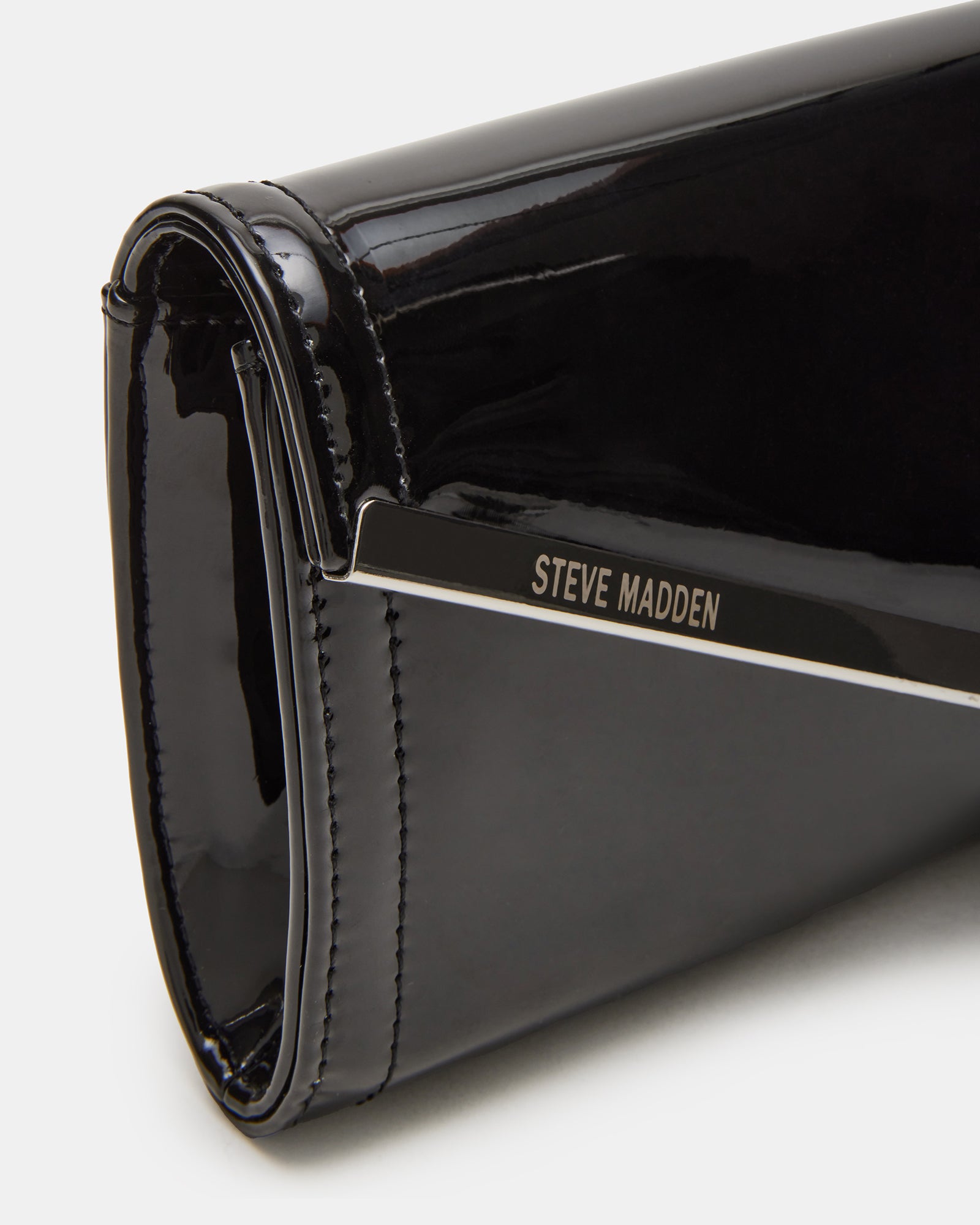 Styled image of the black patent clutch bag paired with elegant evening attire