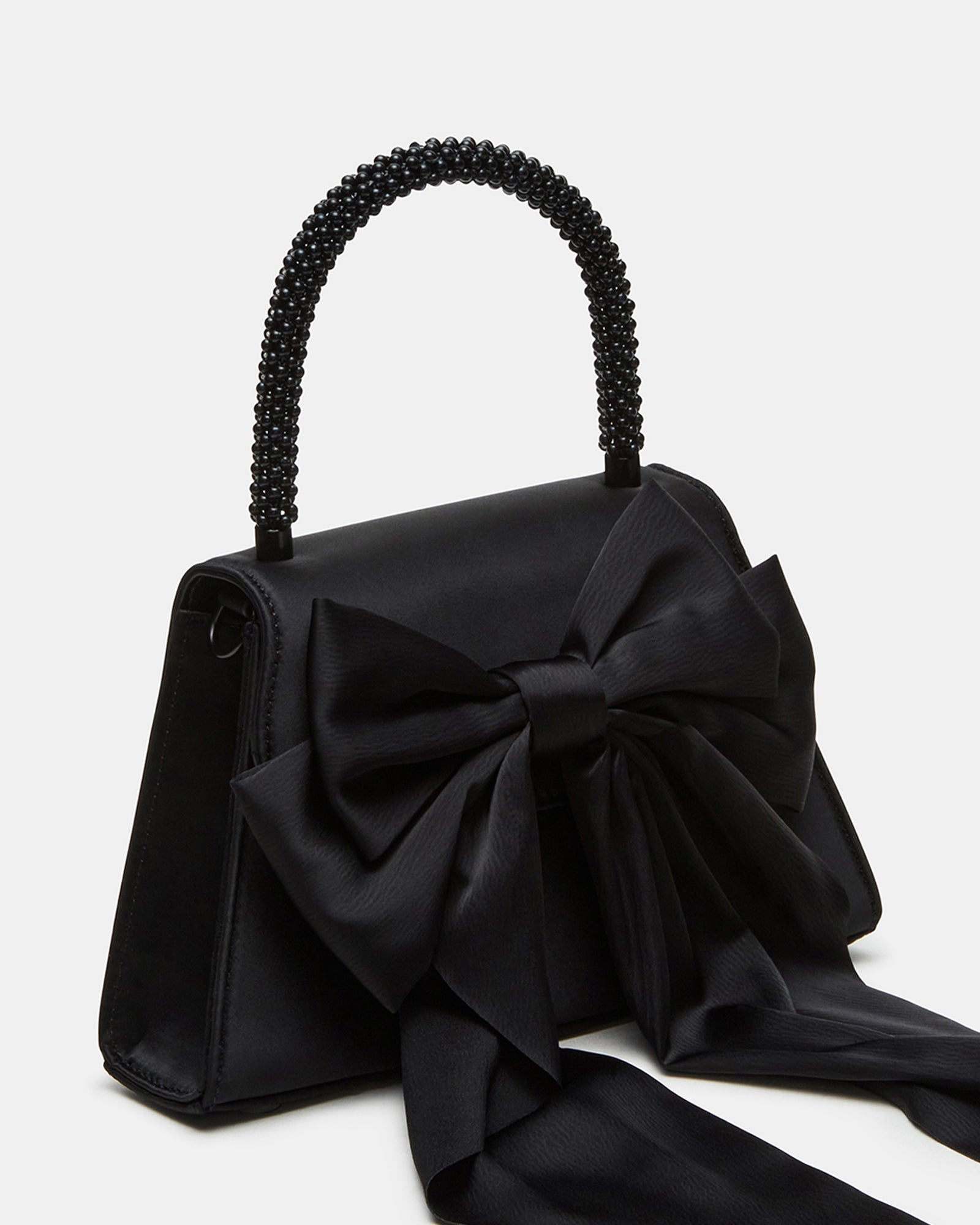 Cosette black satin evening bag displayed on a marble surface with gold jewelry