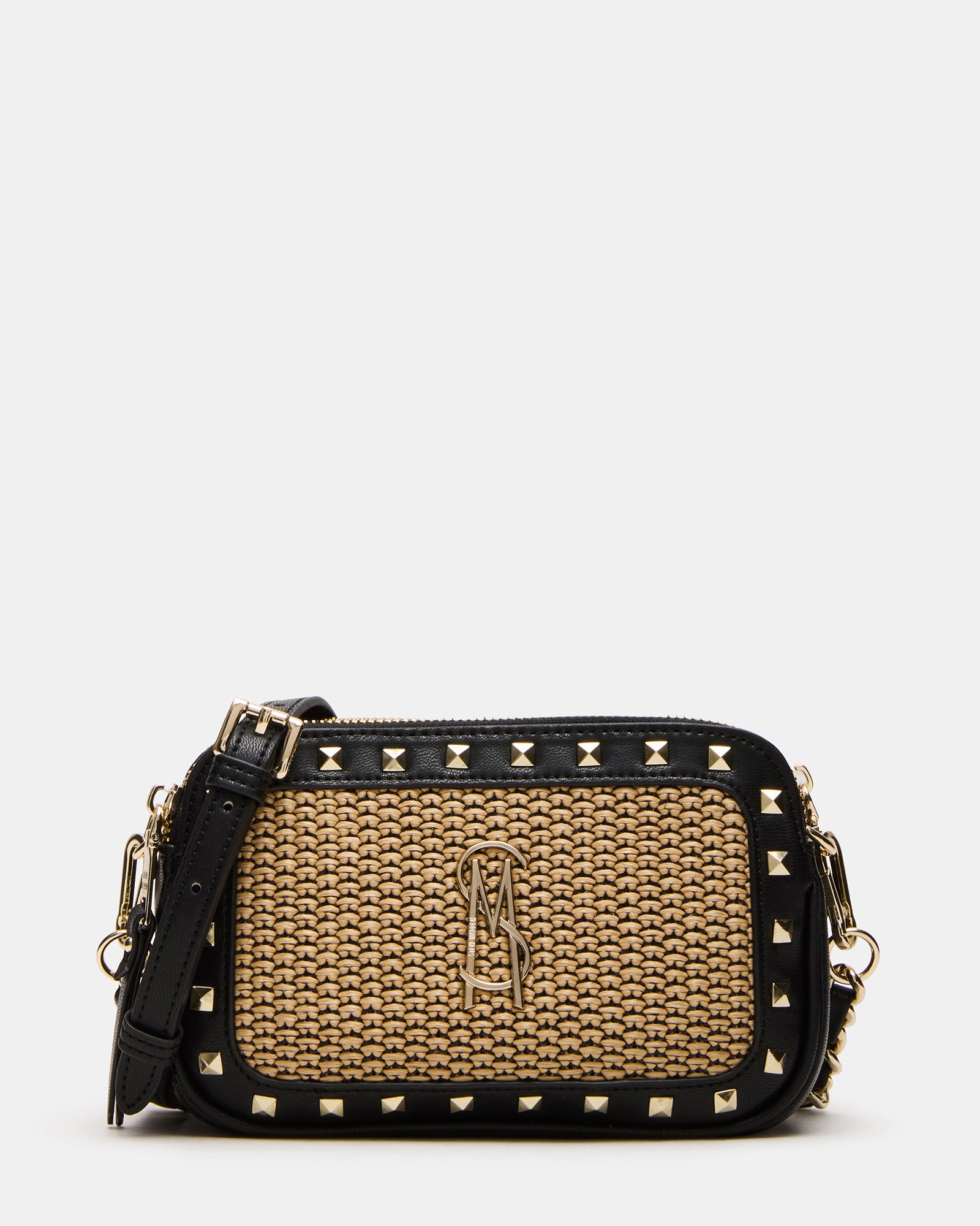 Front view of pyramid stud straw crossbody bag against a cityscape background.