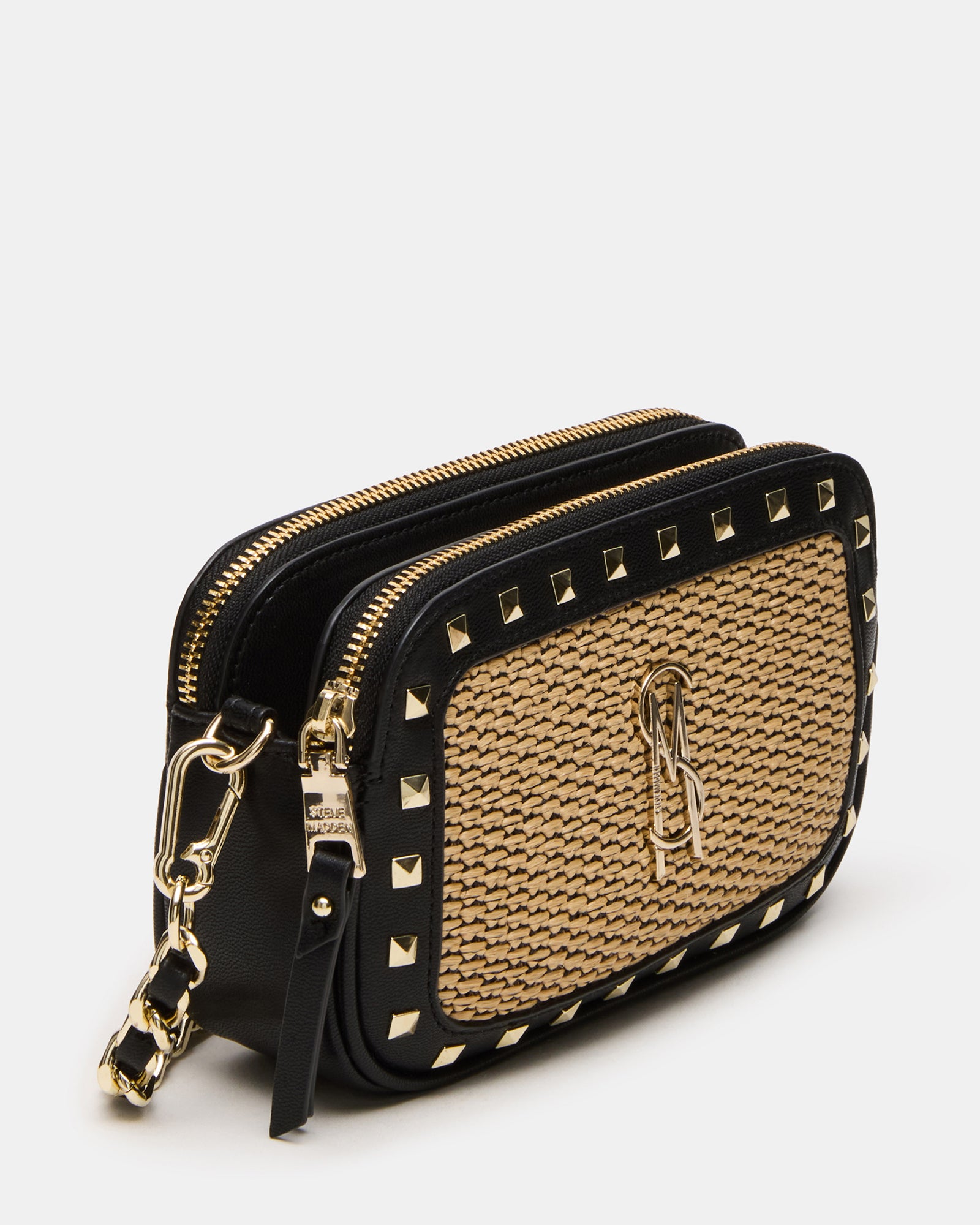 Front view of pyramid stud straw crossbody bag against a cityscape background.