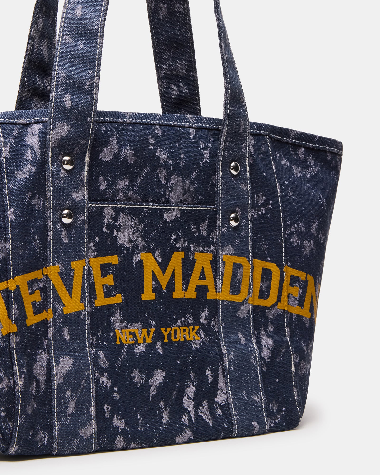 Denim tote bag resting on park bench with sunglasses and book