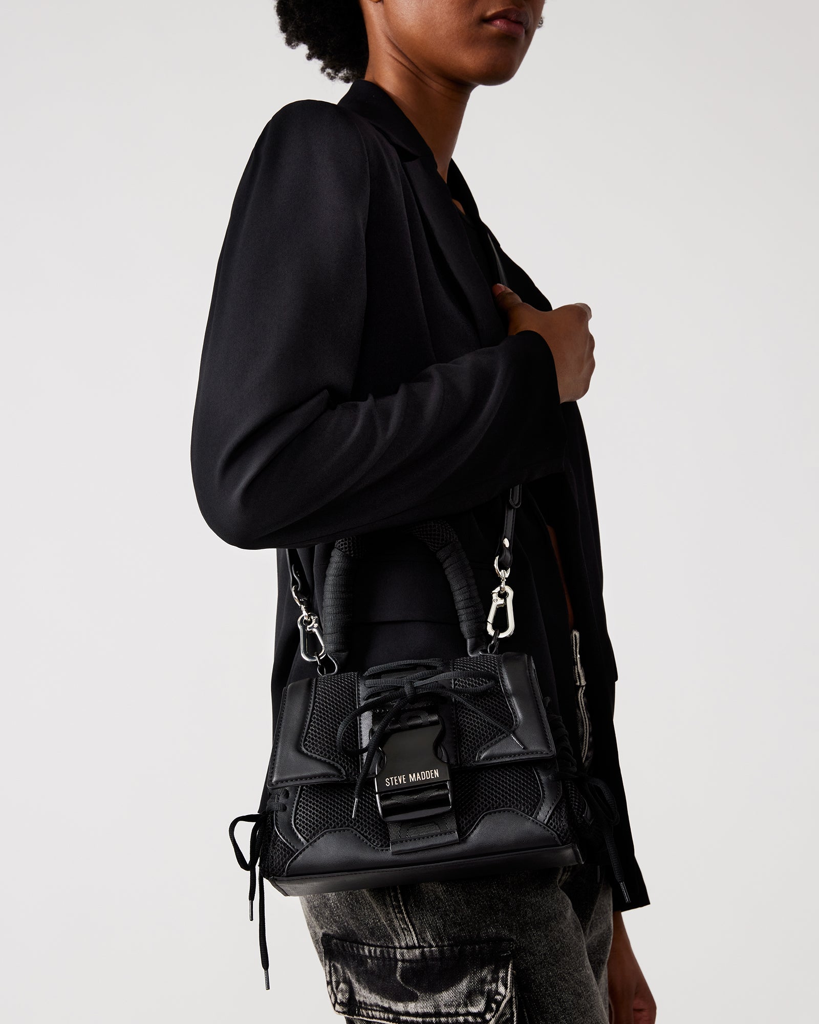 Front view of black trapezoid handbag with chunky buckle and sneaker laces