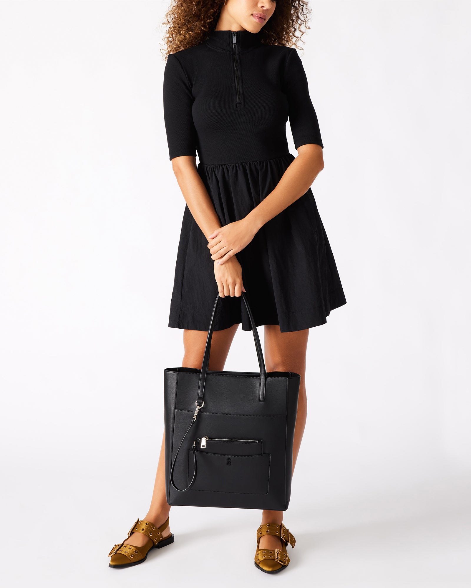 Front view of black handbag on model walking through Soho.
