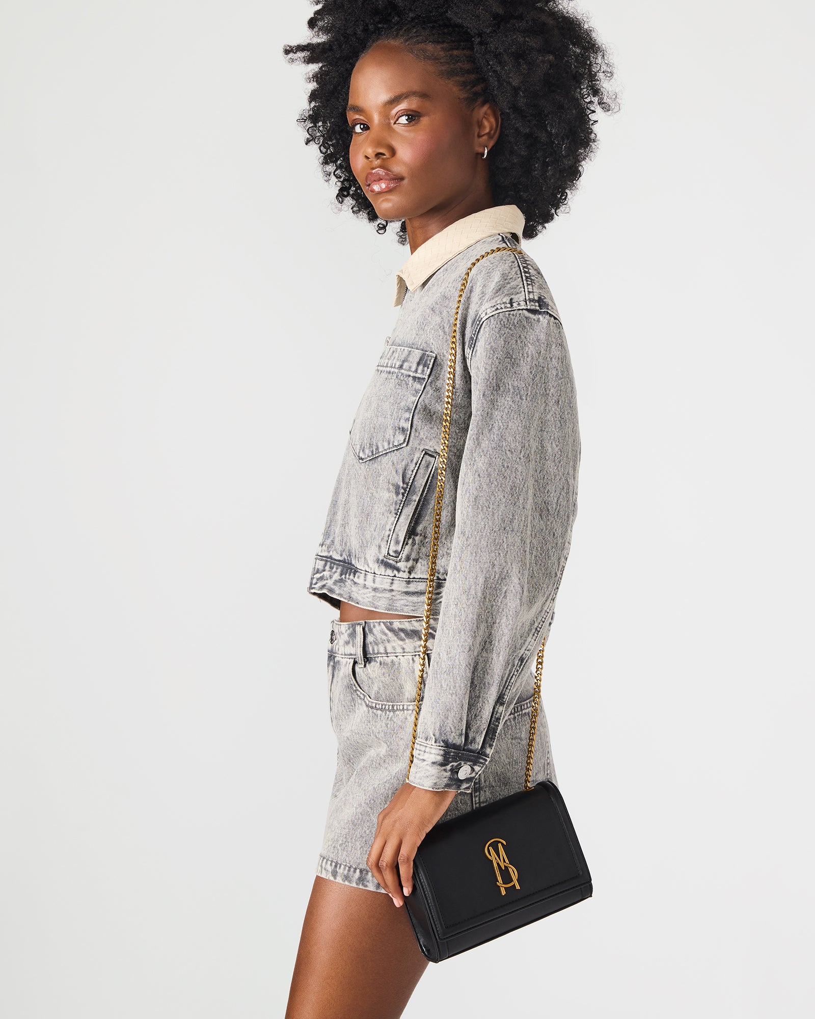 Black leather crossbody bag worn over the shoulder, showcasing magnetic closure.