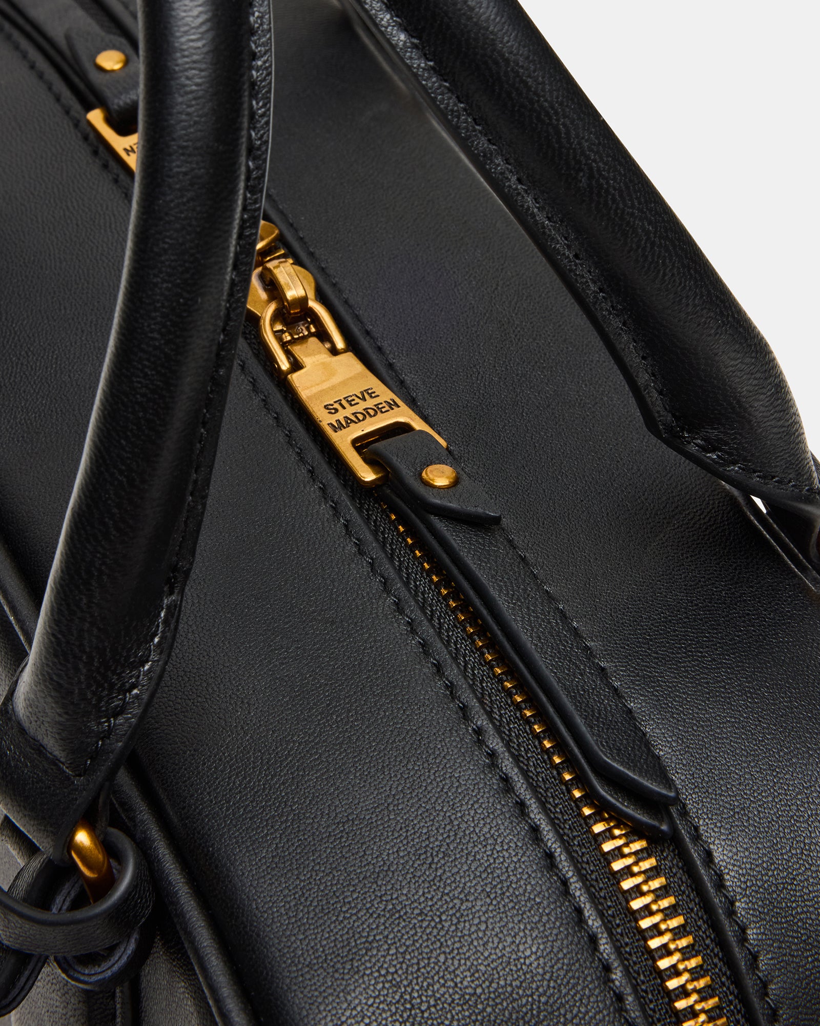 Close-up of buckle detailing on the black leather top-handle bag.