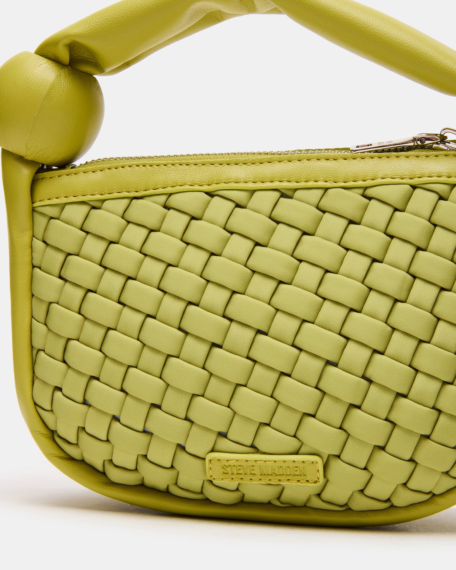Lifestyle shot of the woven handbag being carried, highlighting its compact size.