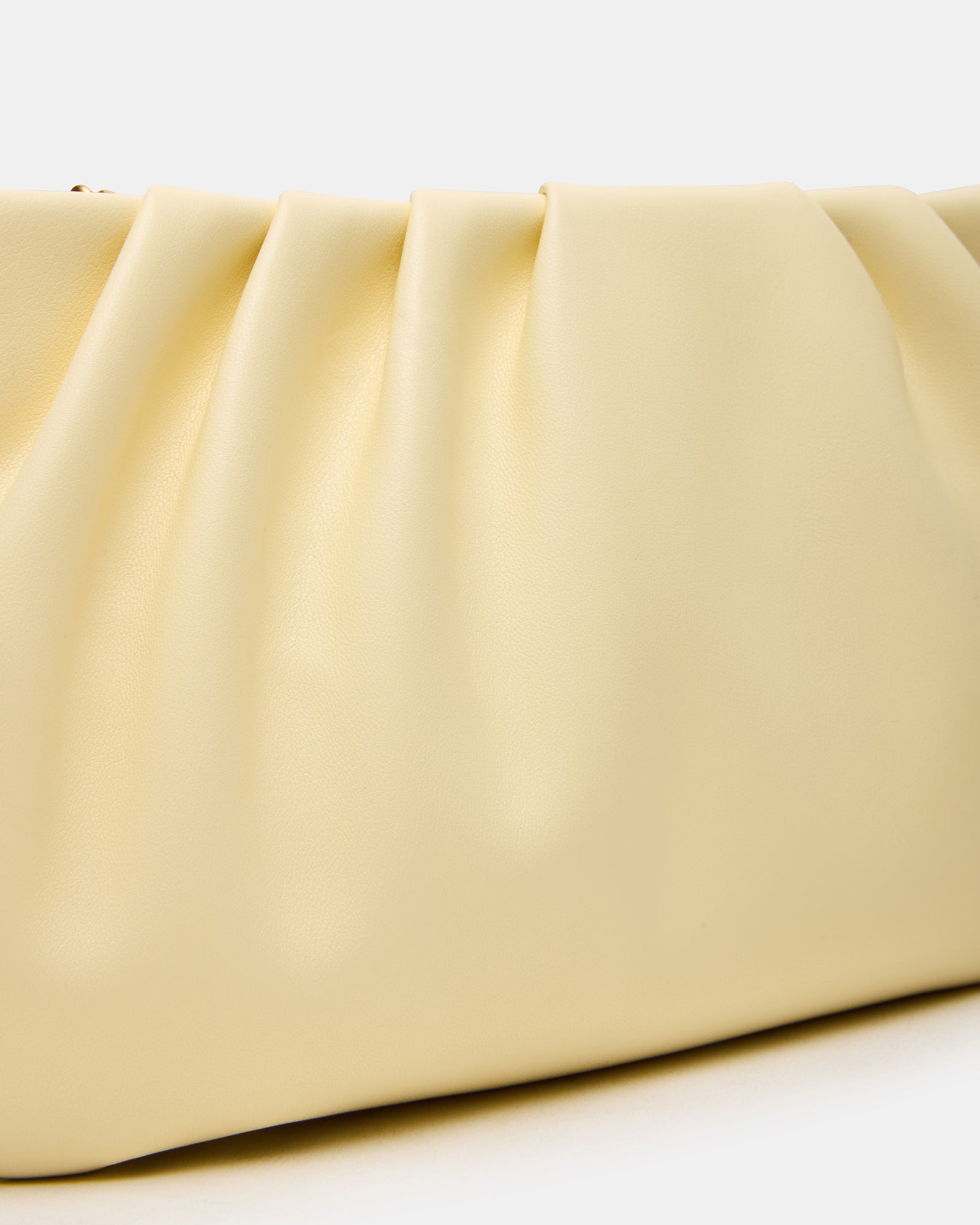 Clutch styled as black crossbody bag worn over shoulder outdoors