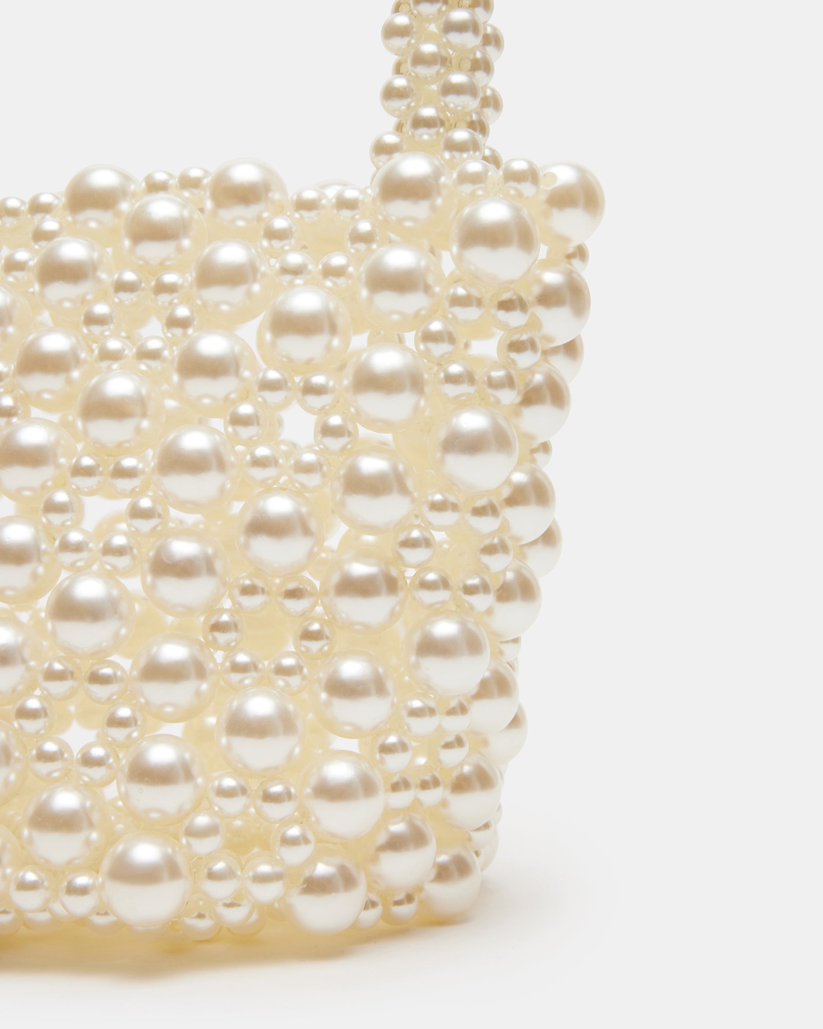 Flat lay of ivory purse alongside pearl accessories for a luxe styling session