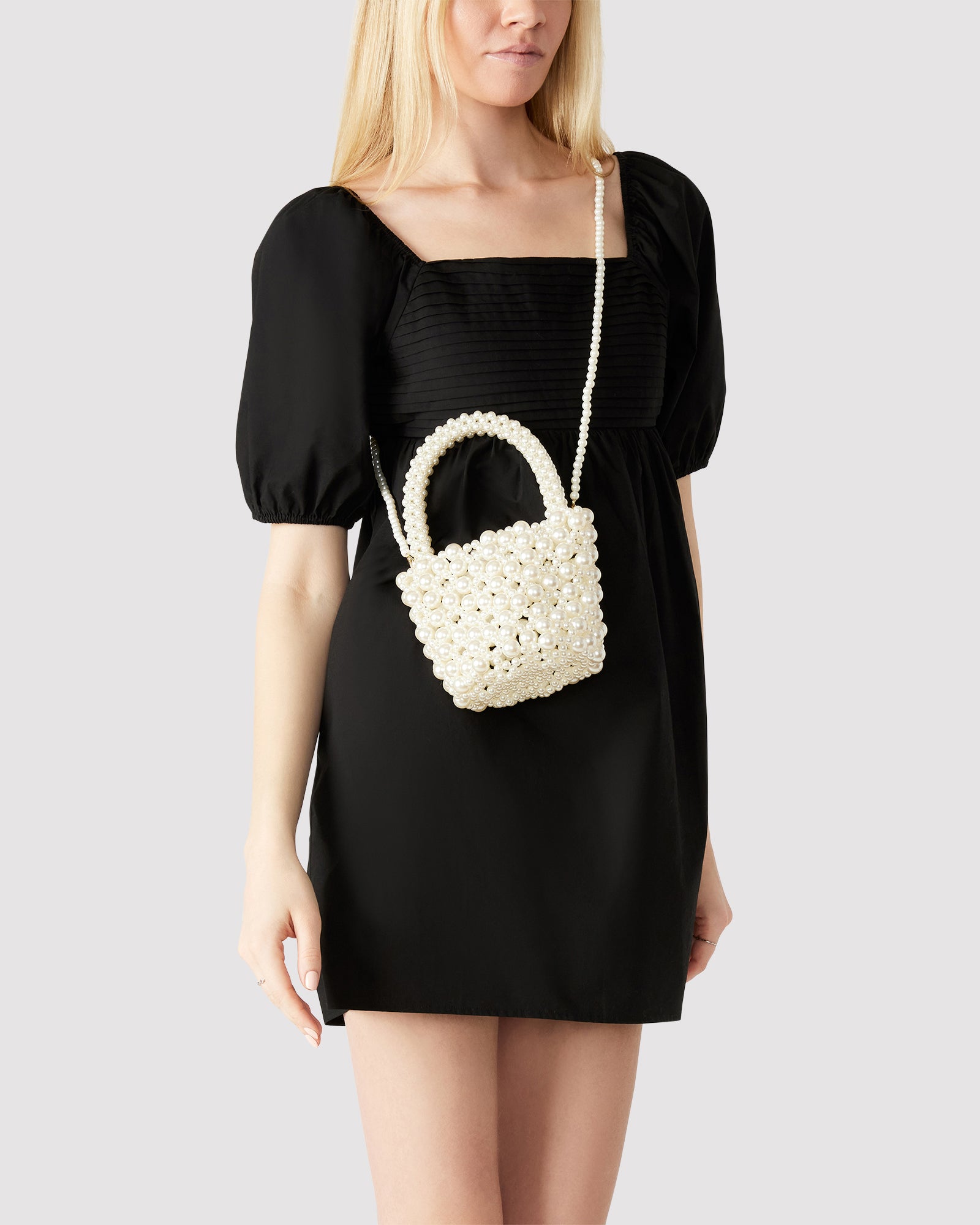 Close-up of faux pearl handle on ivory bucket bag, showcasing pearl detailing