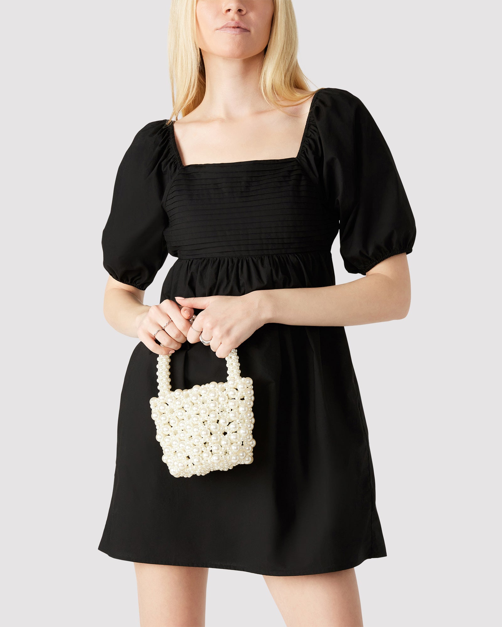 Model carrying the pearl handbag crossbody in a chic urban setting