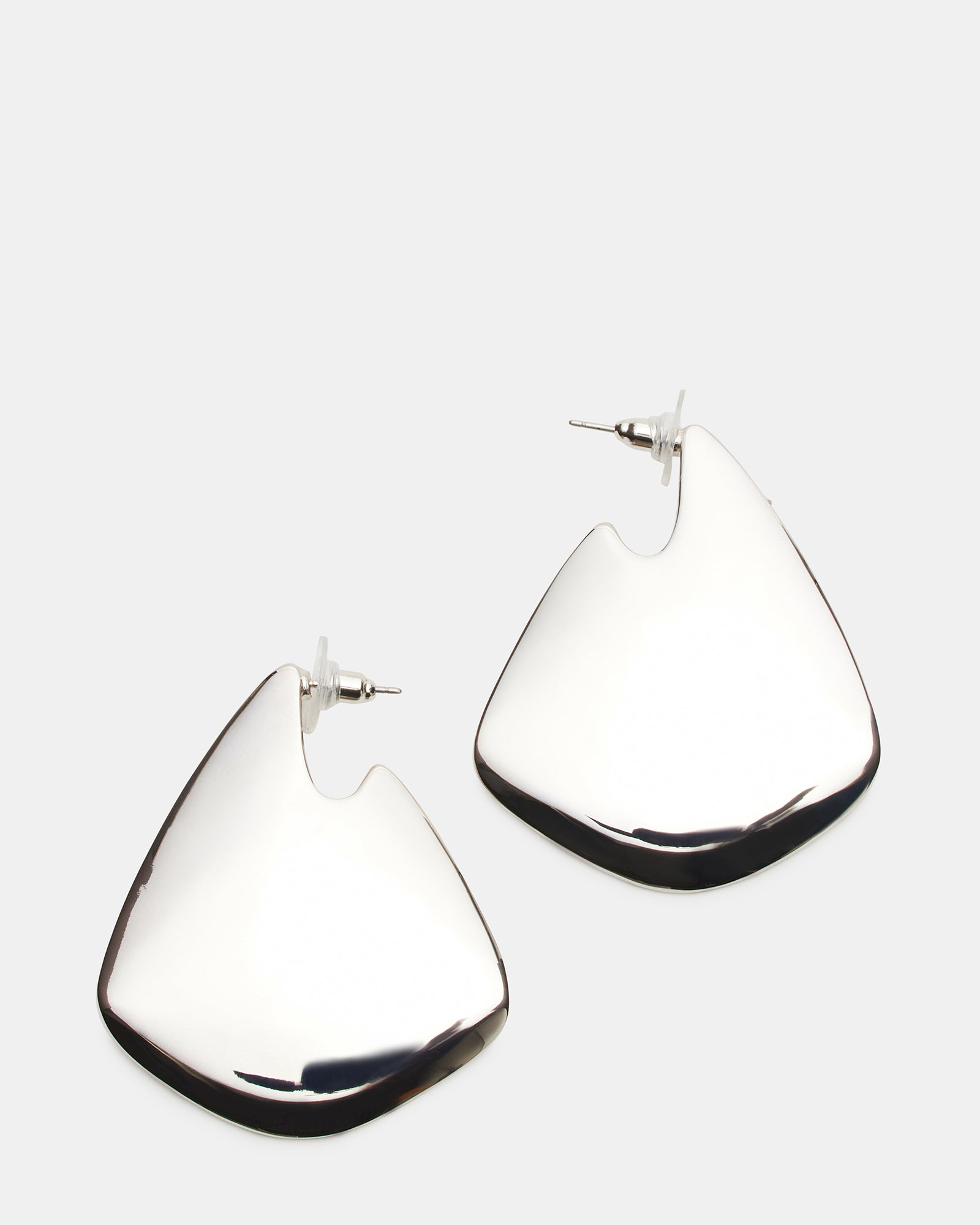 Close-up of silver geometric earrings against neutral background