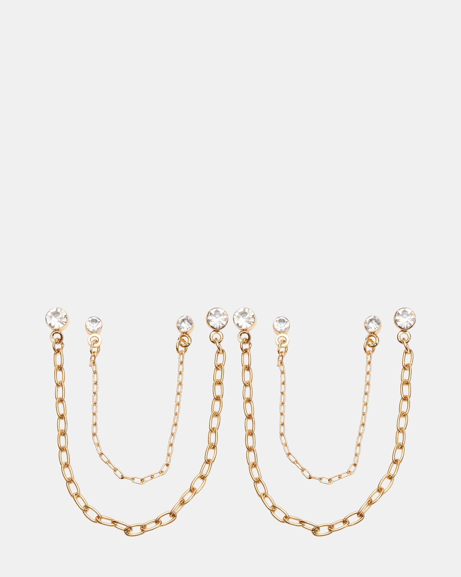 Close-up of crystal drop earrings with gold chains against neutral backdrop