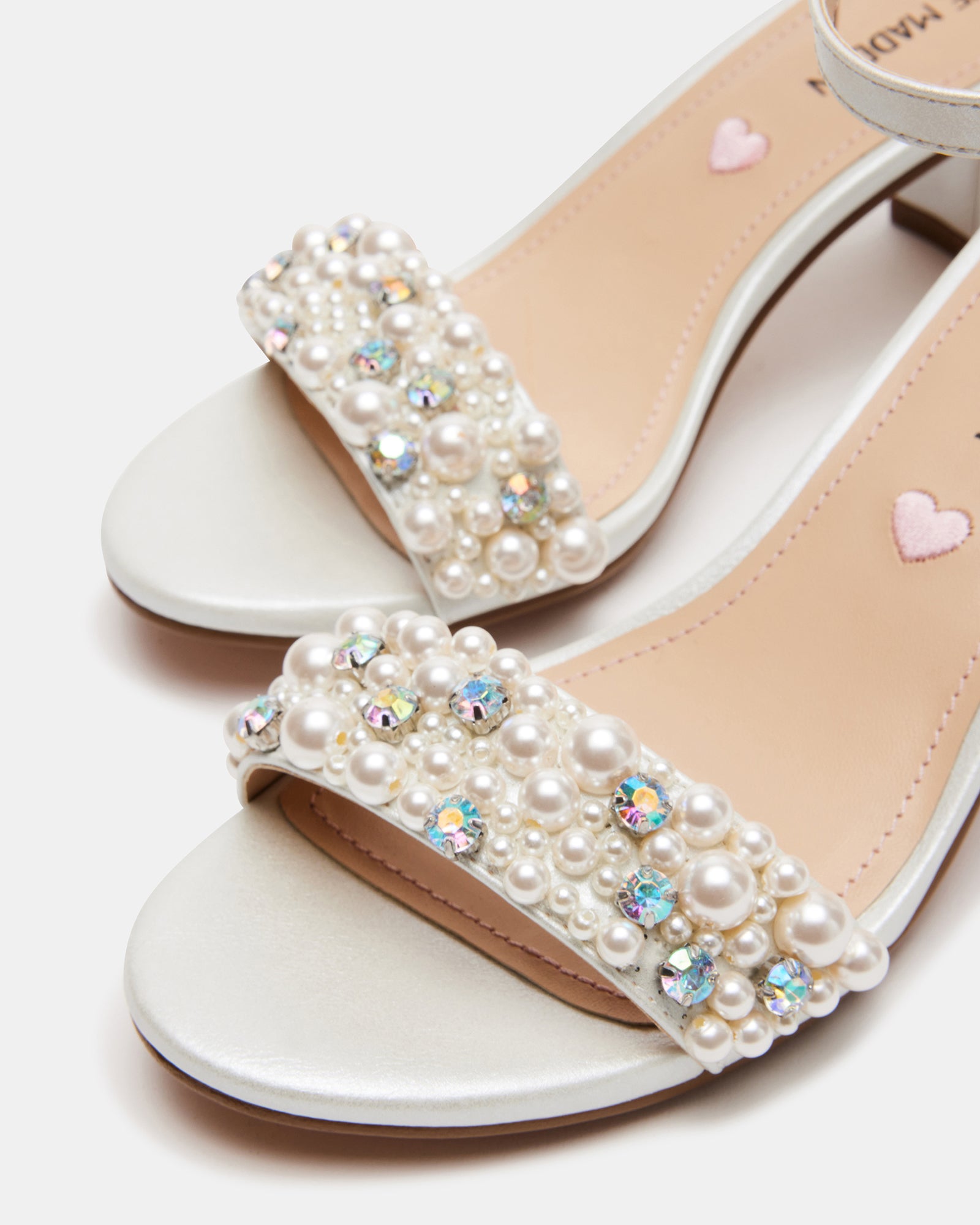 Closeup of white block heel sandals showing ankle buckle and vegan leather