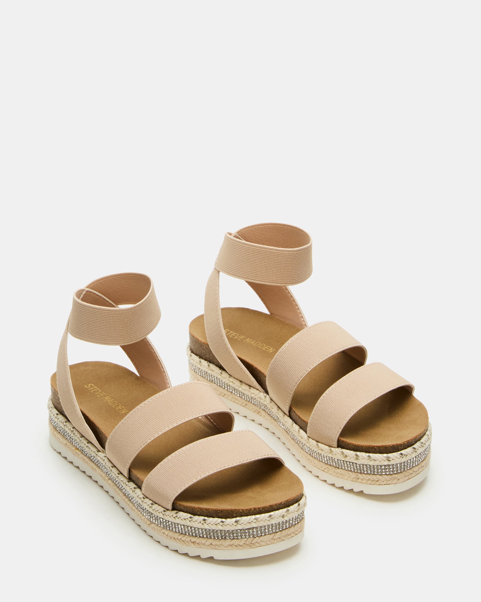 Child wearing beige platform sandals while playing at a sandy park.