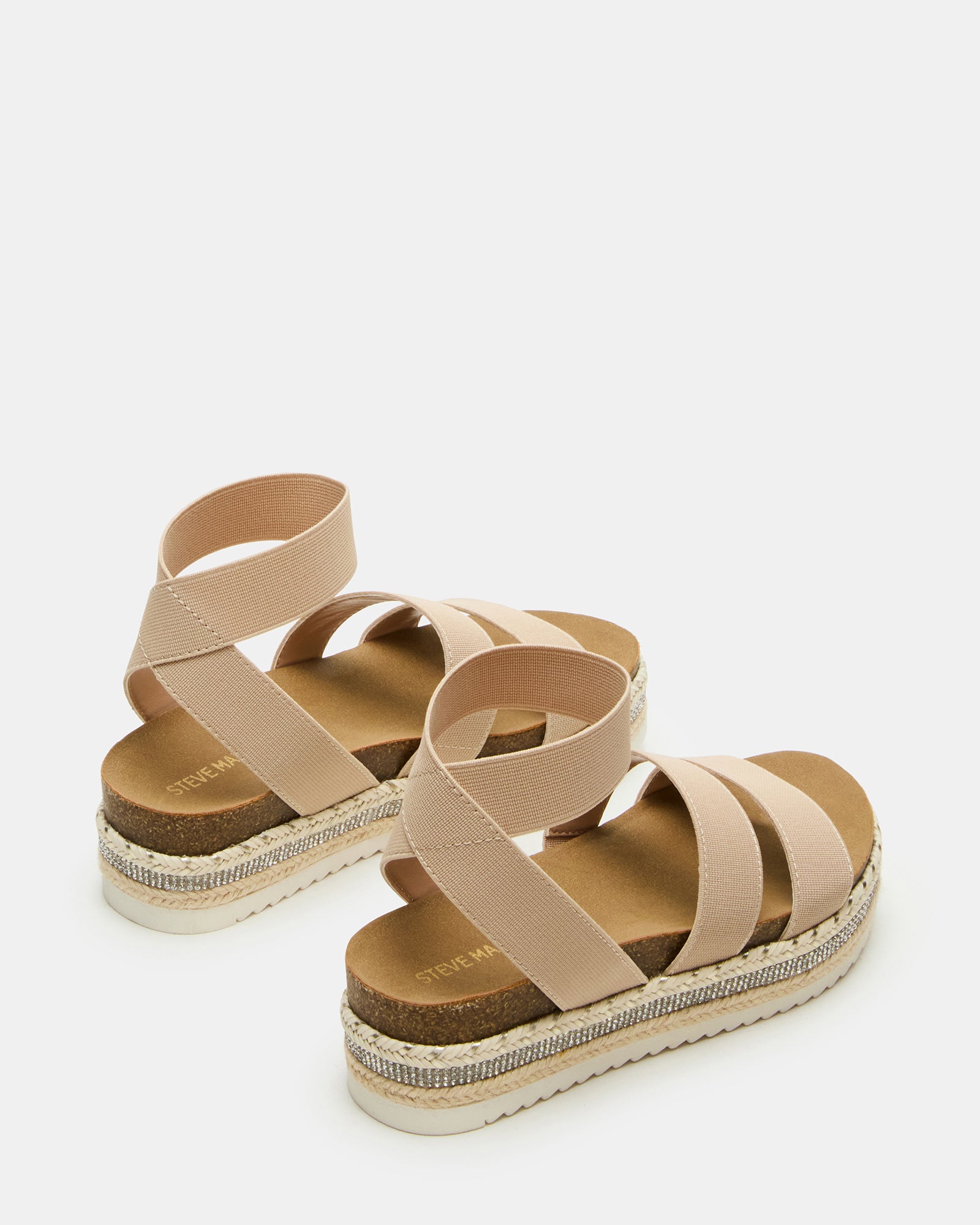 Child wearing beige platform sandals while playing at a sandy park.