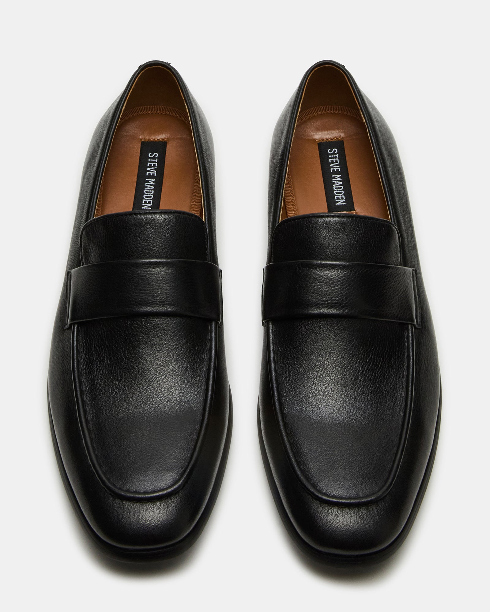Black leather loafers on a hardwood floor, styled for business attire