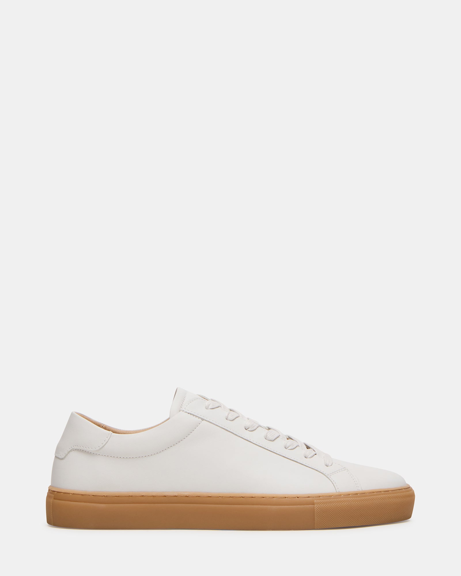 Side profile of white camel sneakers on brick pavement in downtown Columbus
