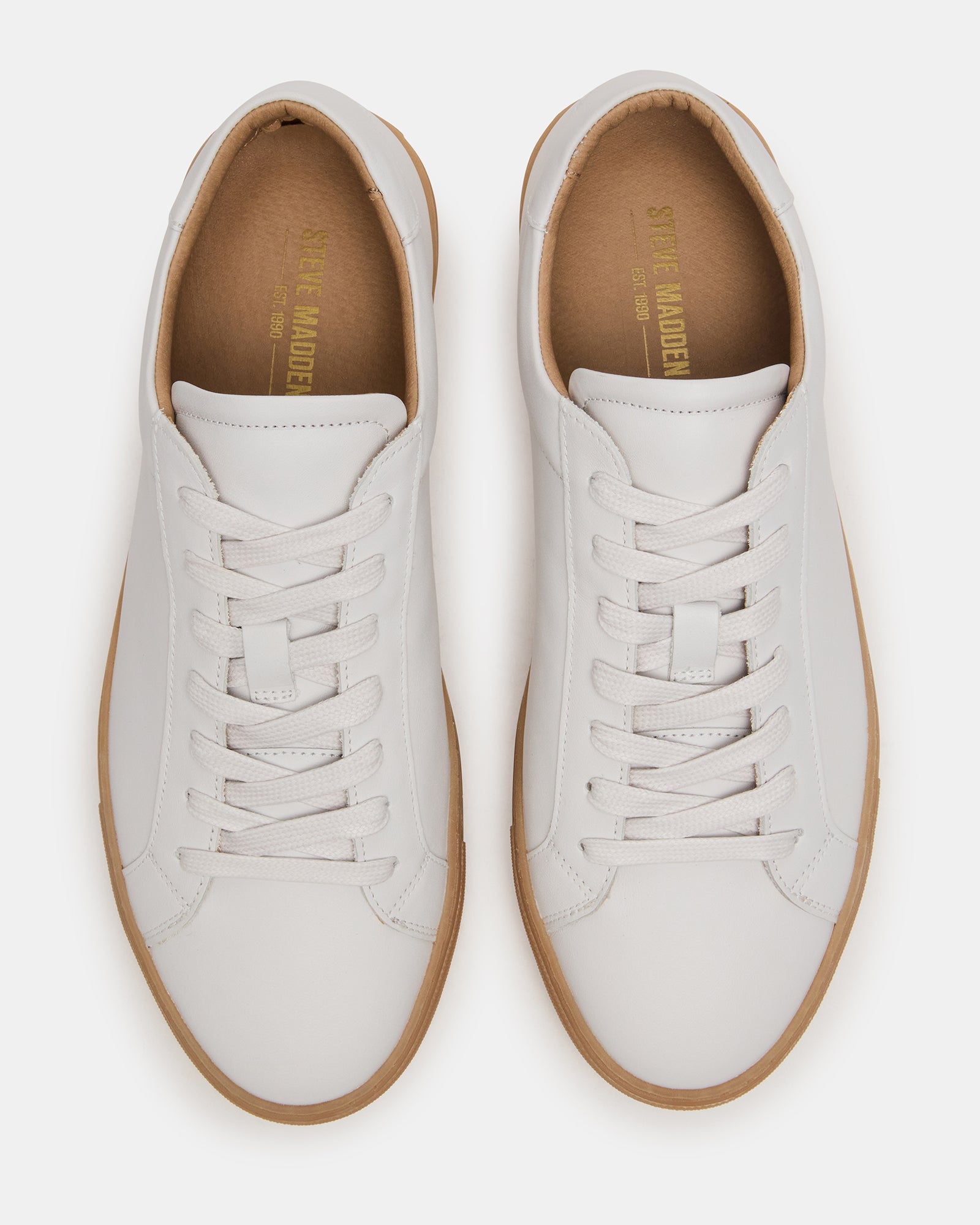 Side profile of white camel sneakers on brick pavement in downtown Columbus