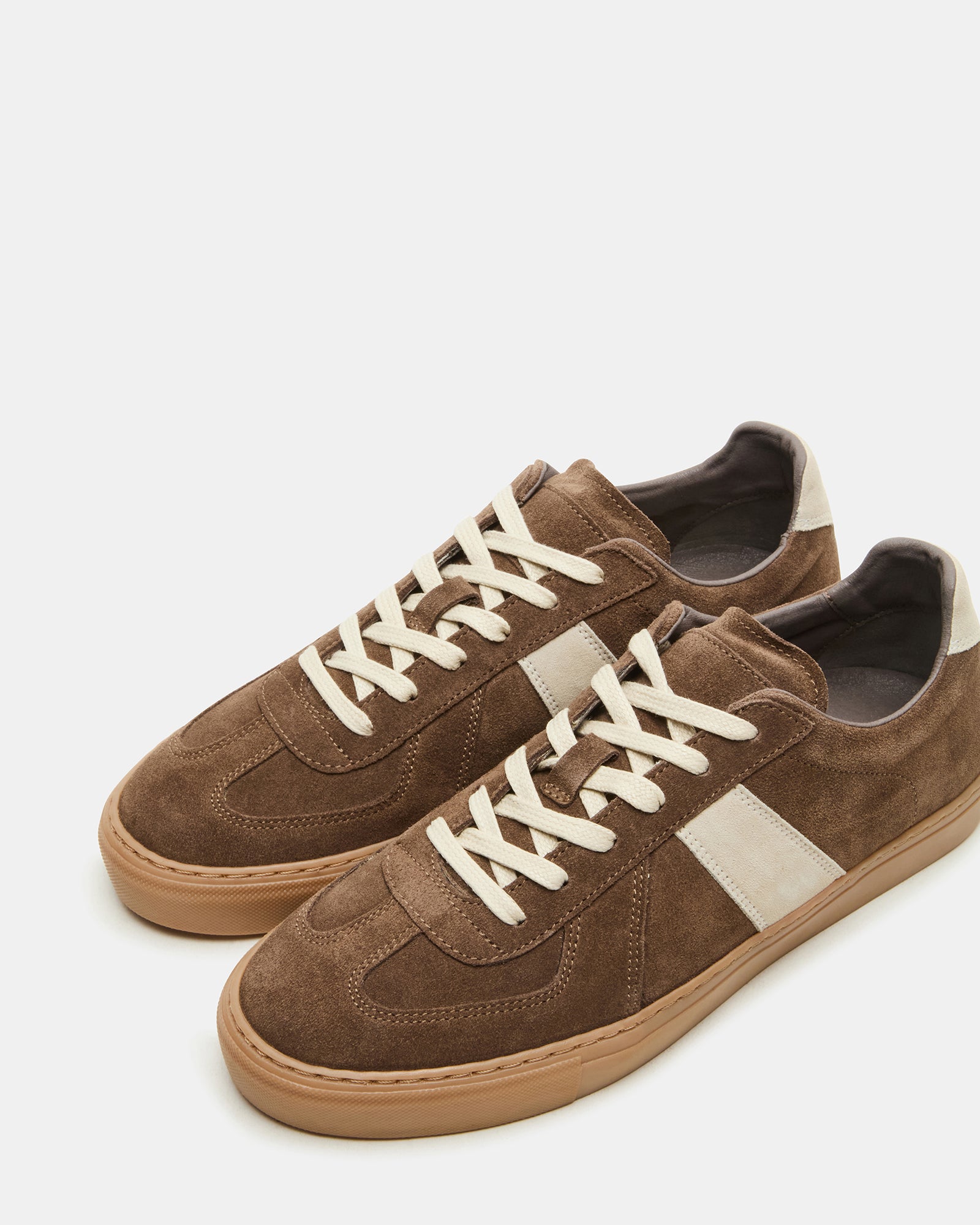 Taupe suede low-top sneakers with lace-up closure on a wooden background