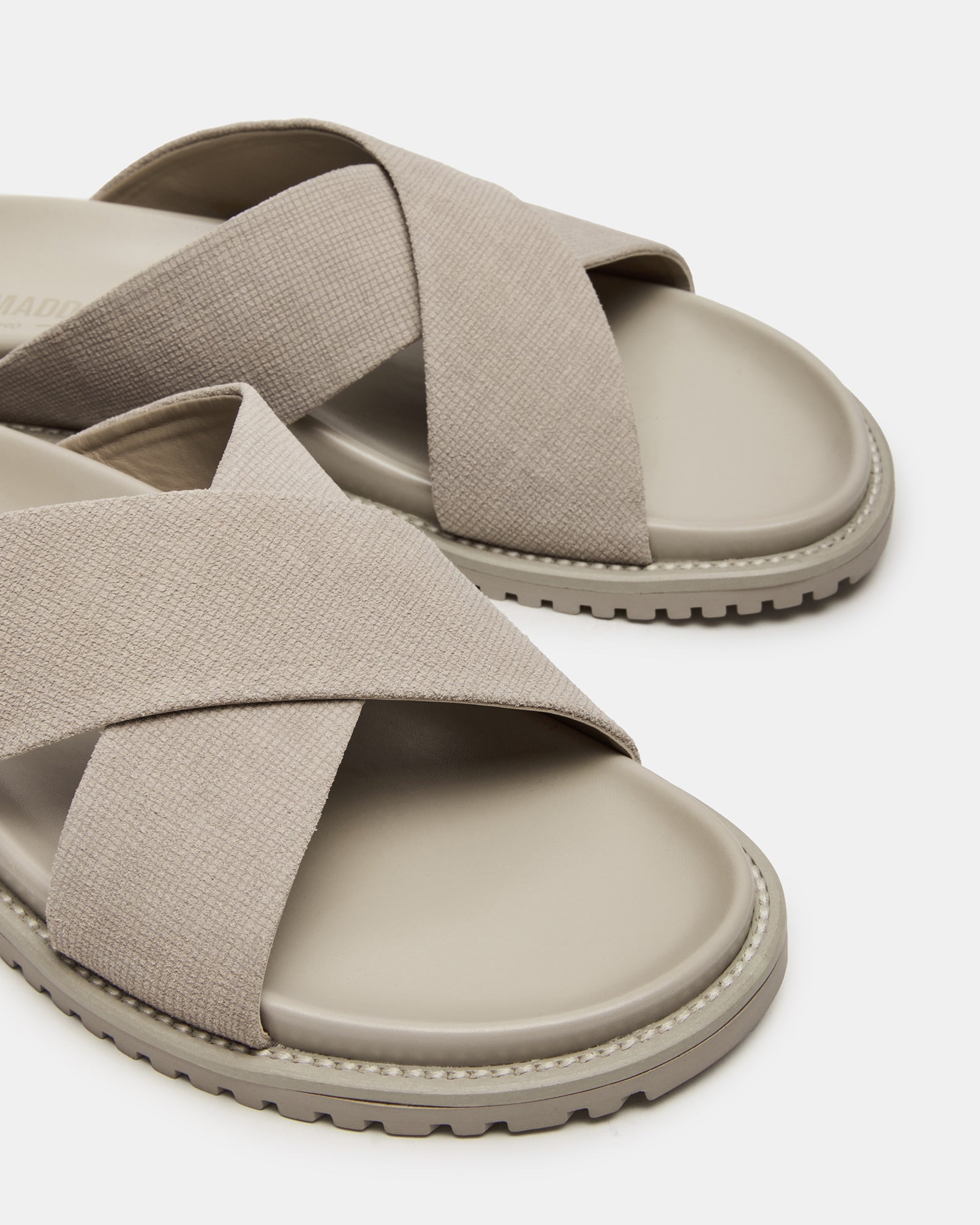 Close-up of black flat sandals highlighting the elegant crisscross pattern.