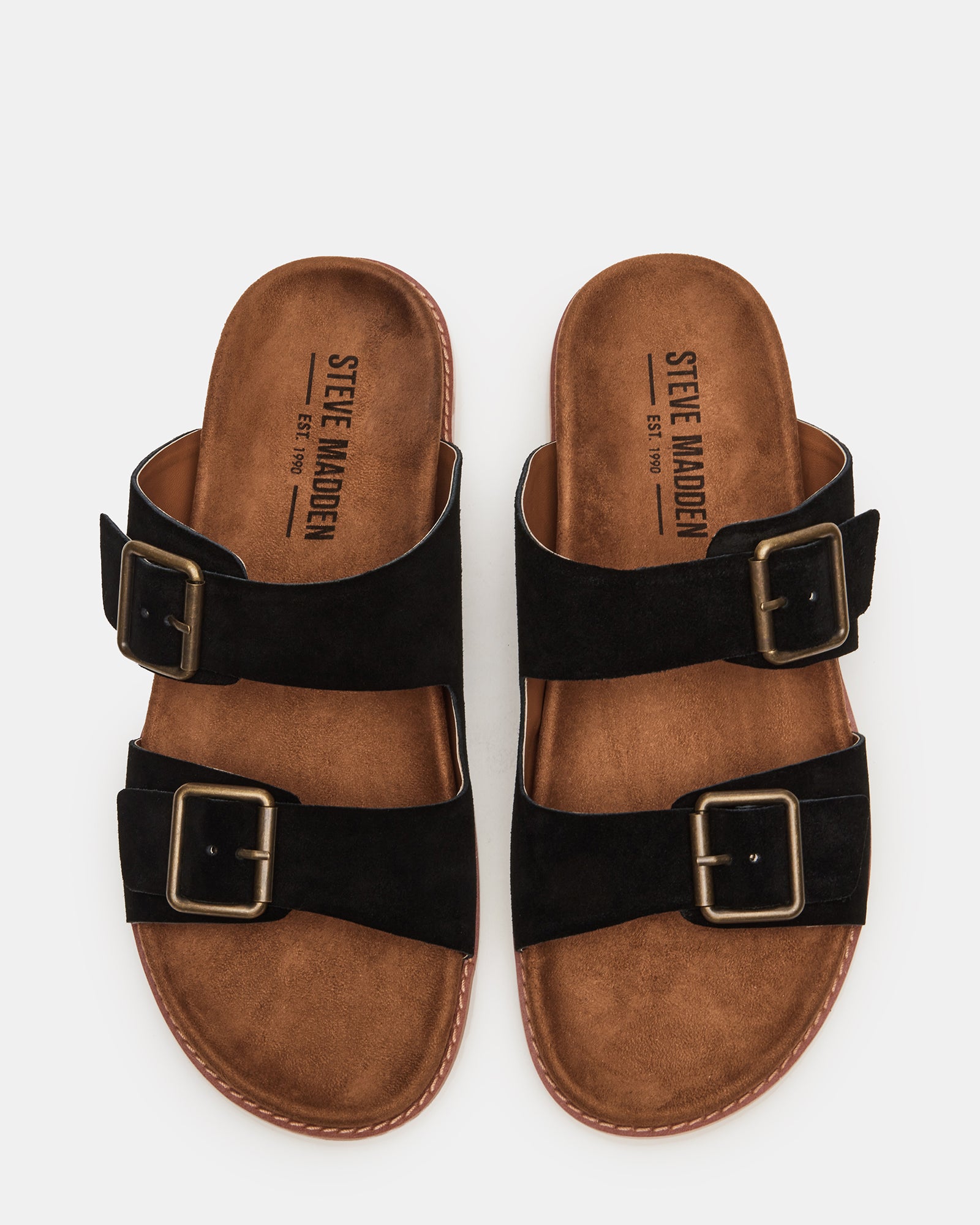 Close-up of black suede slide sandals showing buckle detail and rubber sole