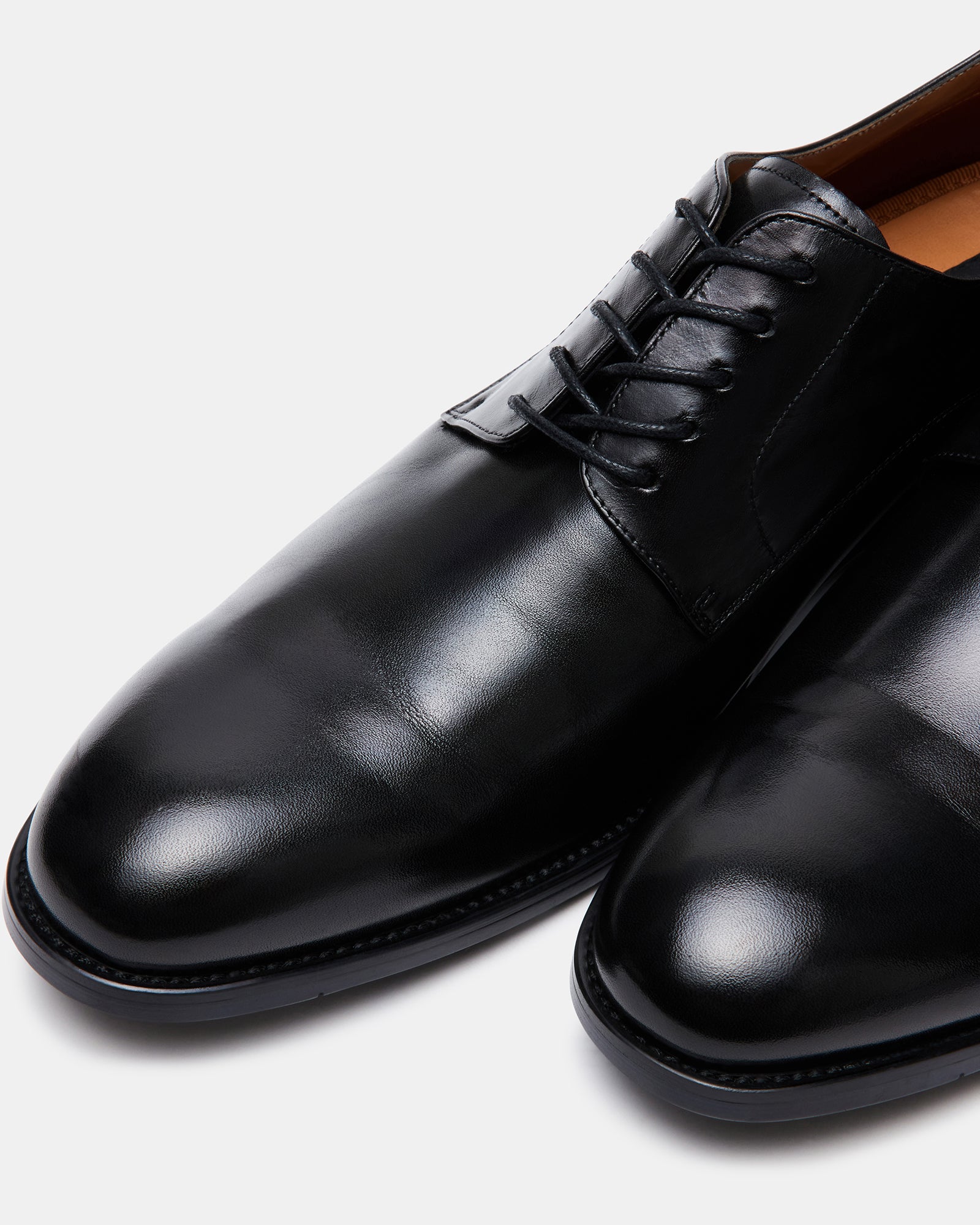 Close-up of black leather derby shoes with polished finish, showcasing detailed lacing