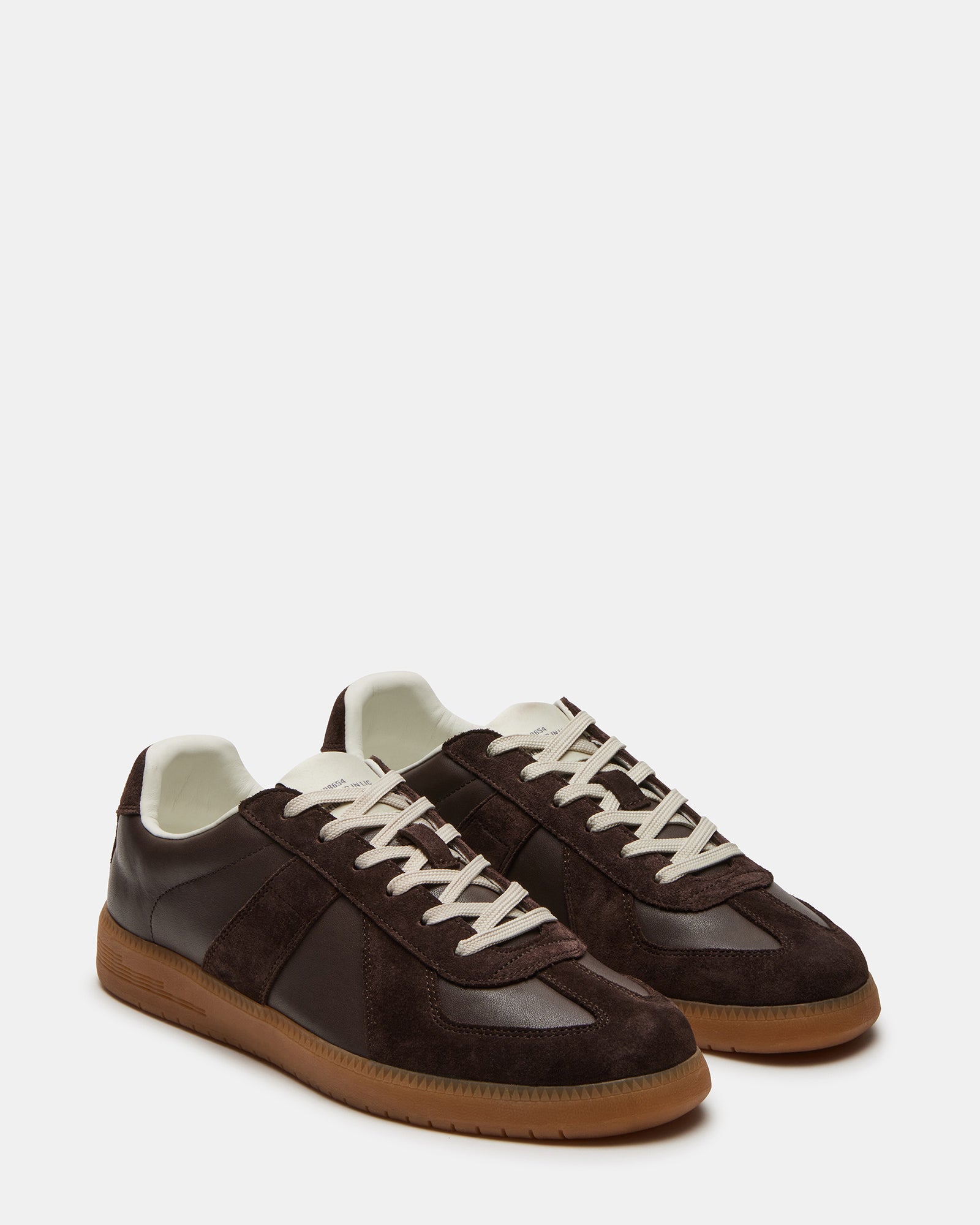 Close-up heel shot of black leather sneakers on a concrete backdrop